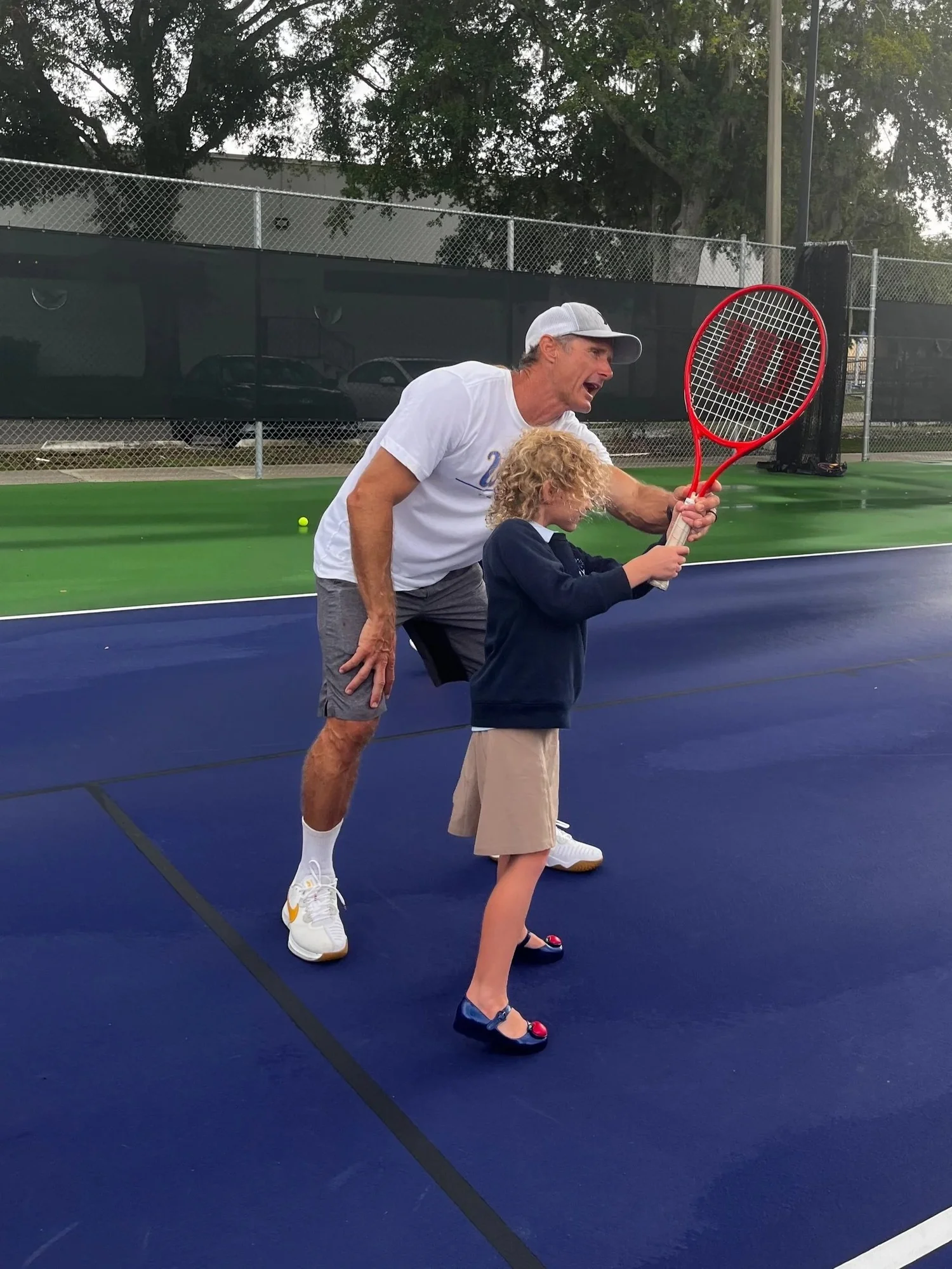 A coach helping a child with their tennis swing at Shalom Orlando