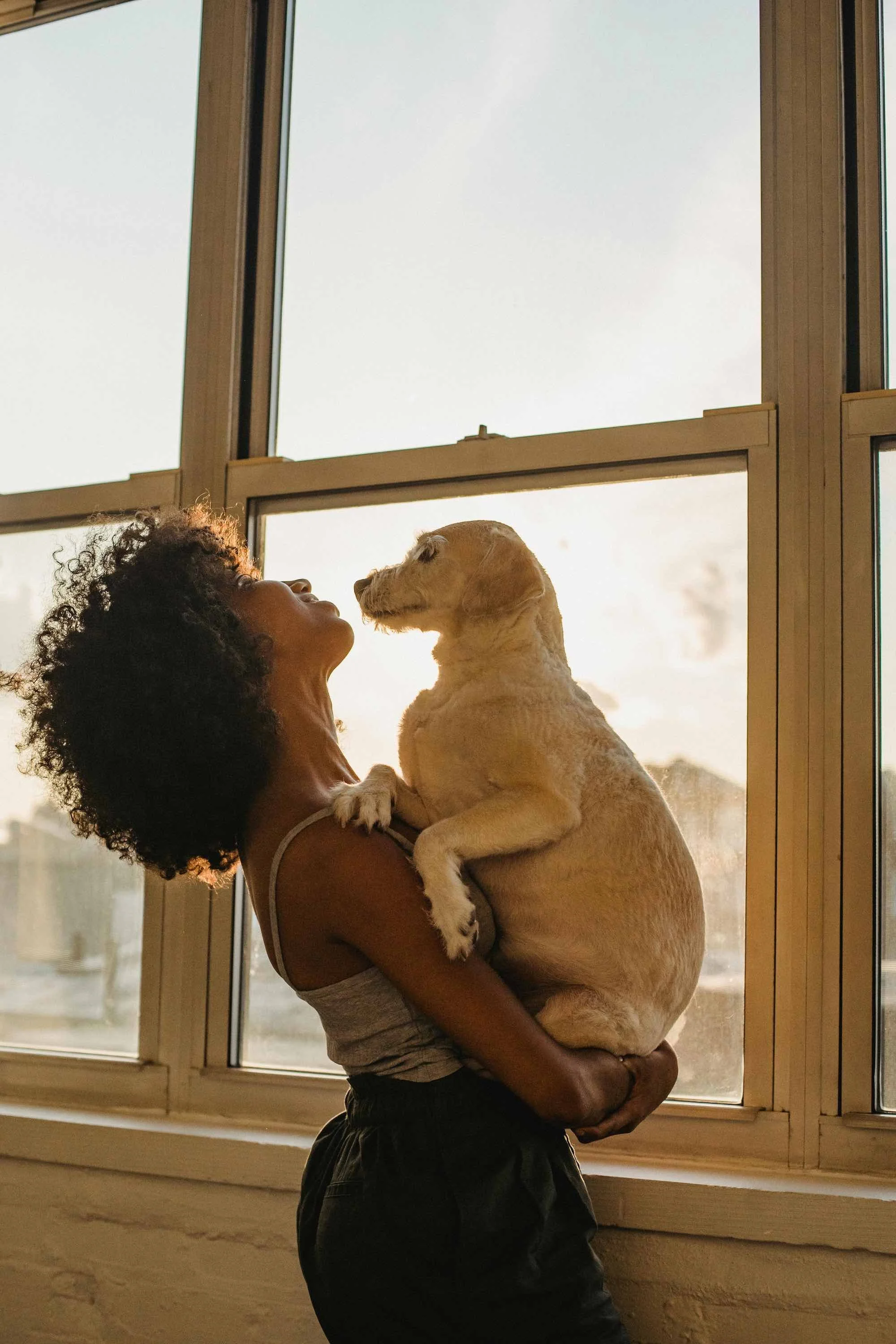 Woman holding her dog in front of a window