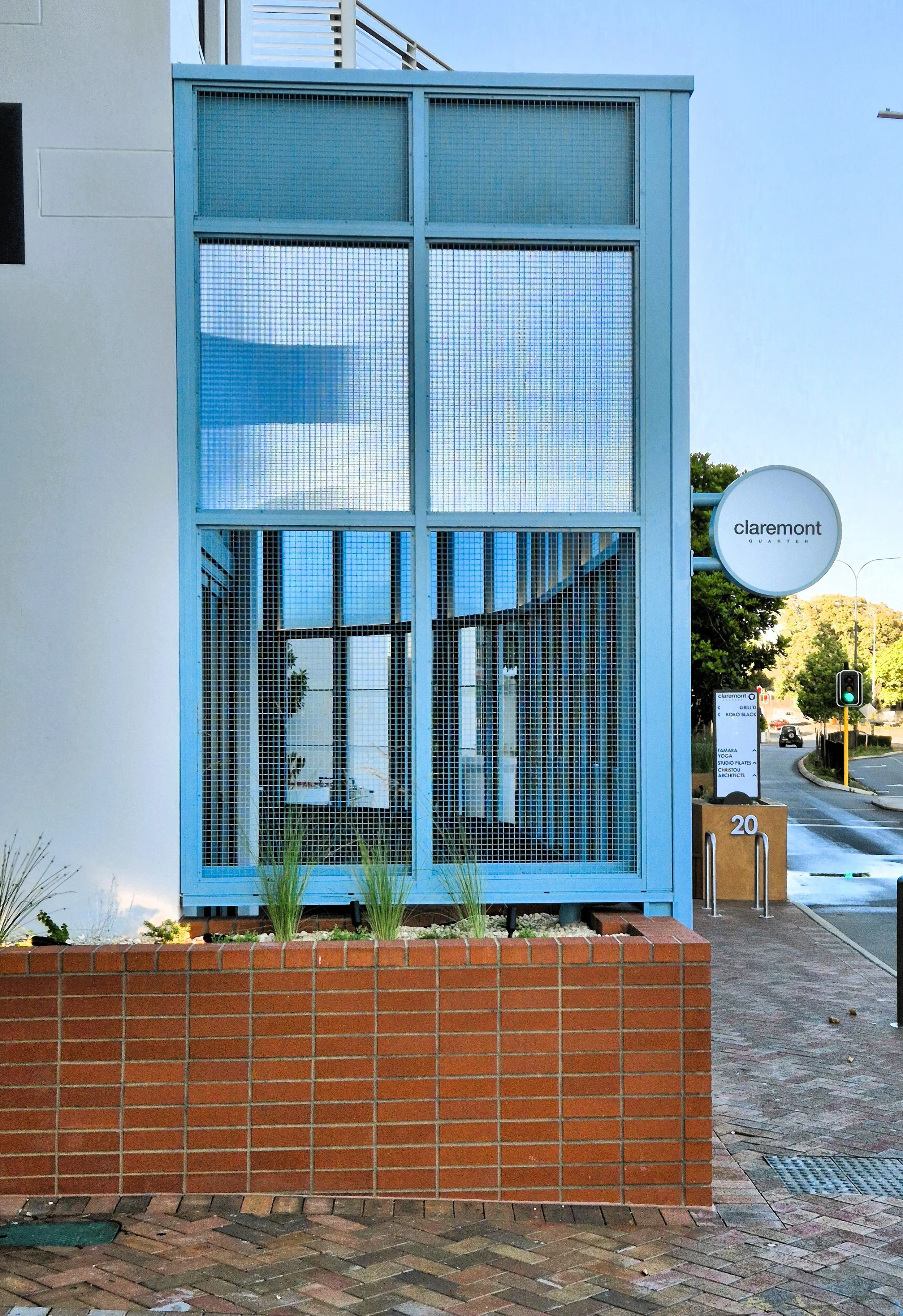 Blue building with a sign that says 'Claremont Quarter' and the number 20 on a brick planter in front.