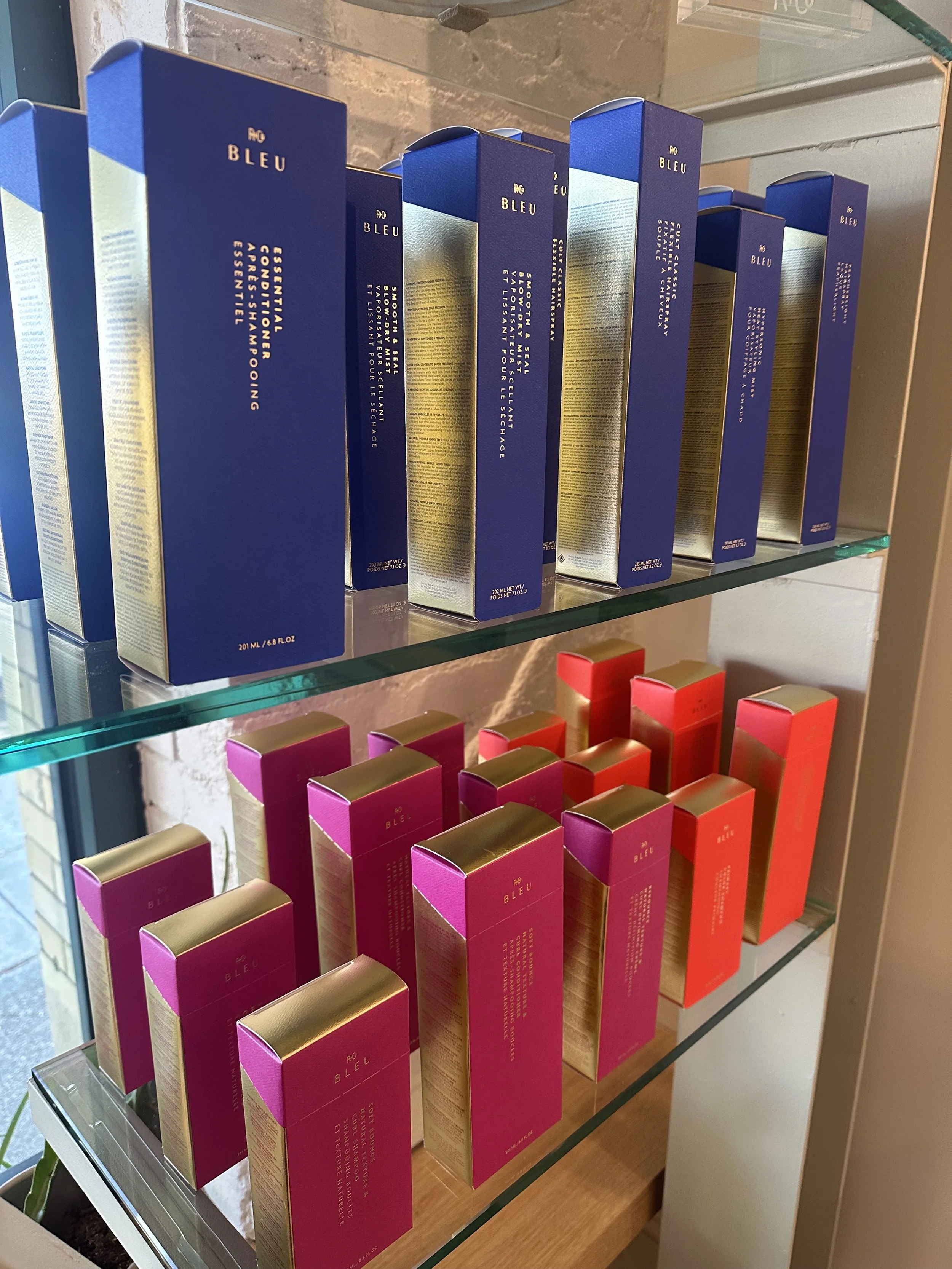 Shelf displaying boxed products in blue and pink packaging with gold accents at a store.