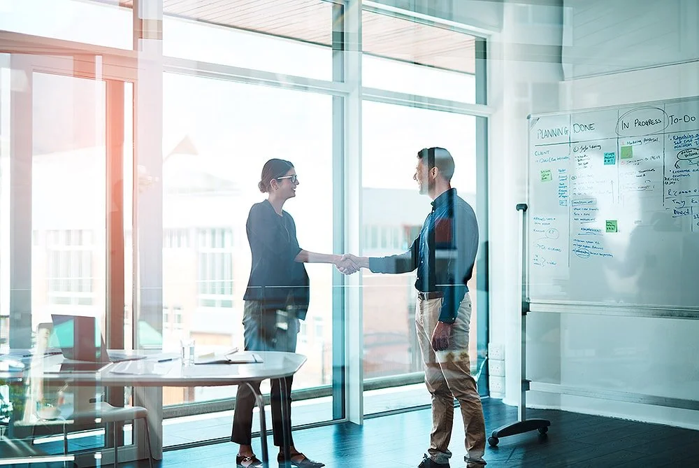 Two executives giving a handshake in a office setting.
