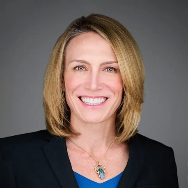 Portrait of Jonielle Dedman wearing a black dress jacket, blue top and matching blue necklace.