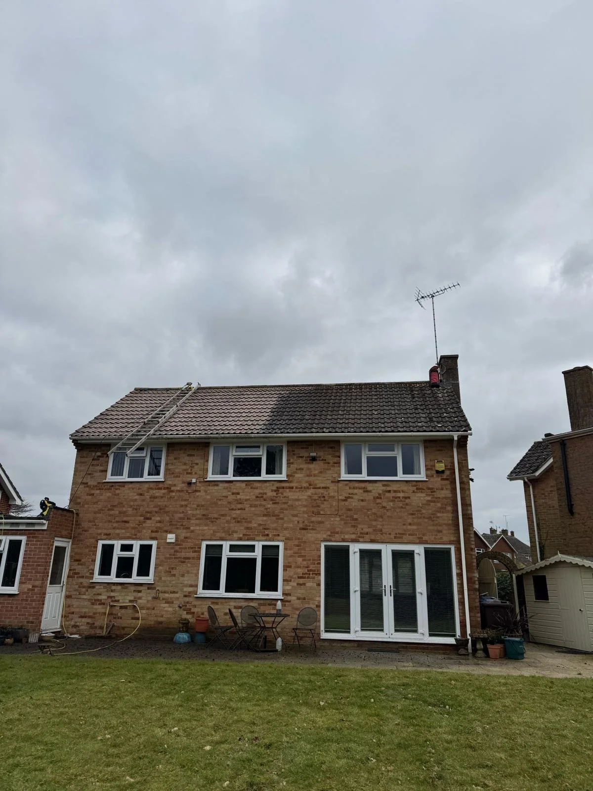 Ground-level view showing roof mid-way through the de-mossing process in Cranleigh.