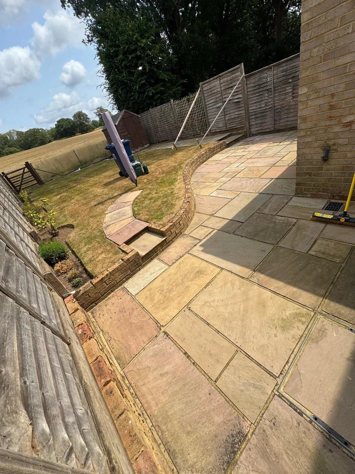 Wide view of sandstone patio affected by black spot, algae and fading before deep cleaning.