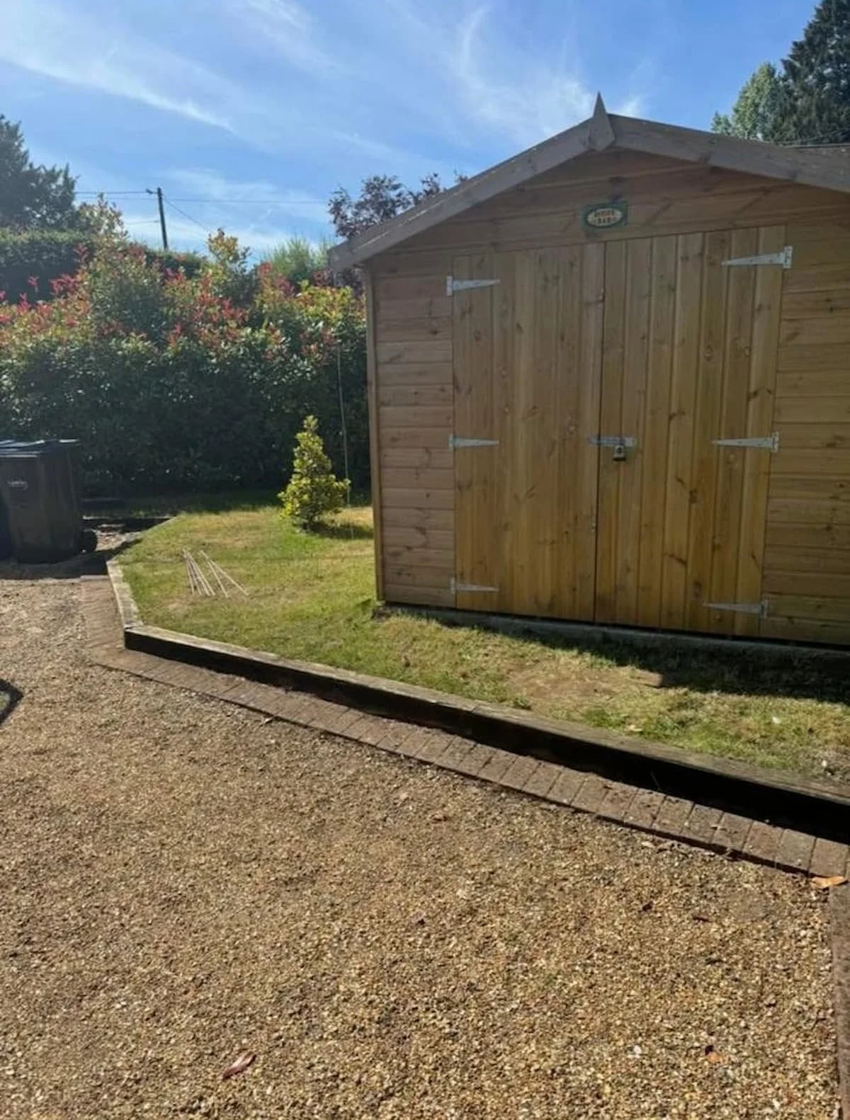 Finished garden shed installed on the new concrete base with timber edging retaining the lawn.