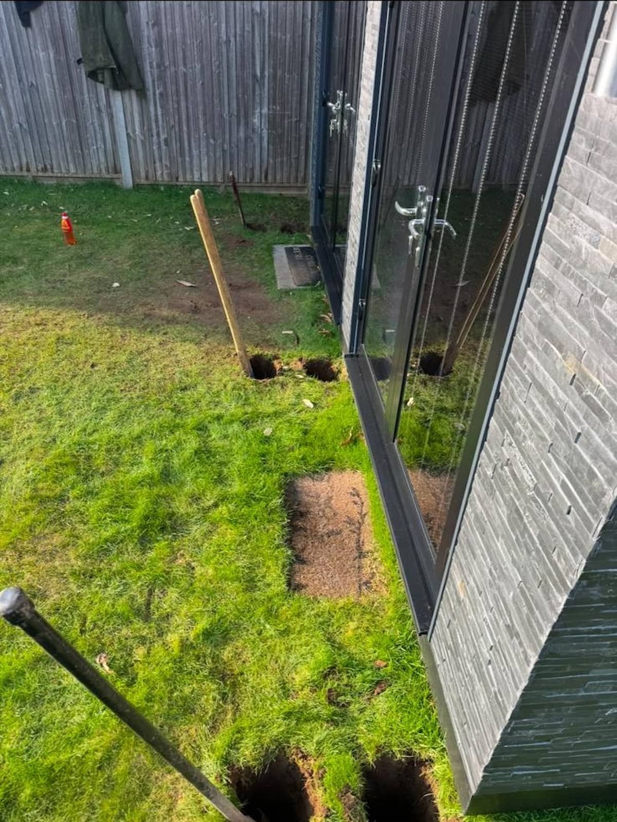 Post holes prepared for the decking step foundations beside the garden office.