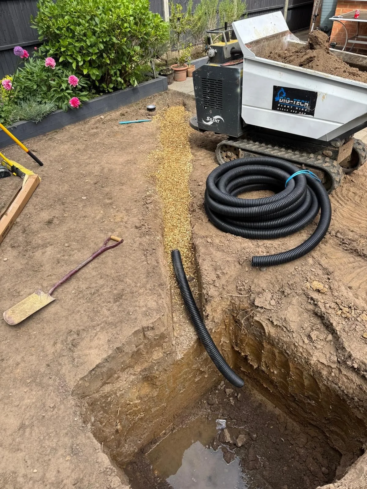 Perforated drainage pipe laid on compacted gravel base for the soakaway.