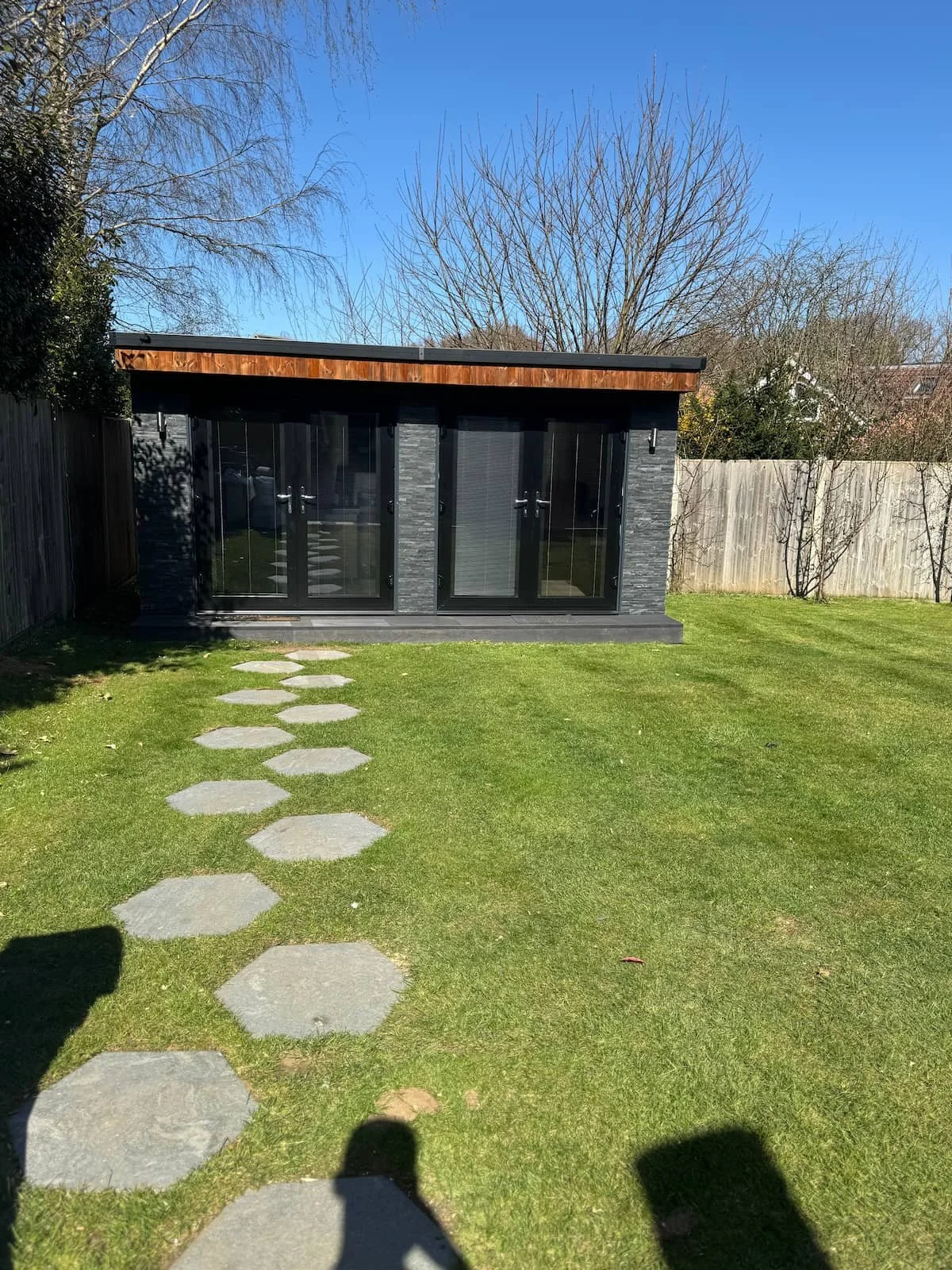 Full view of the completed Witley project with decking step, treated cladding and stone walkway.