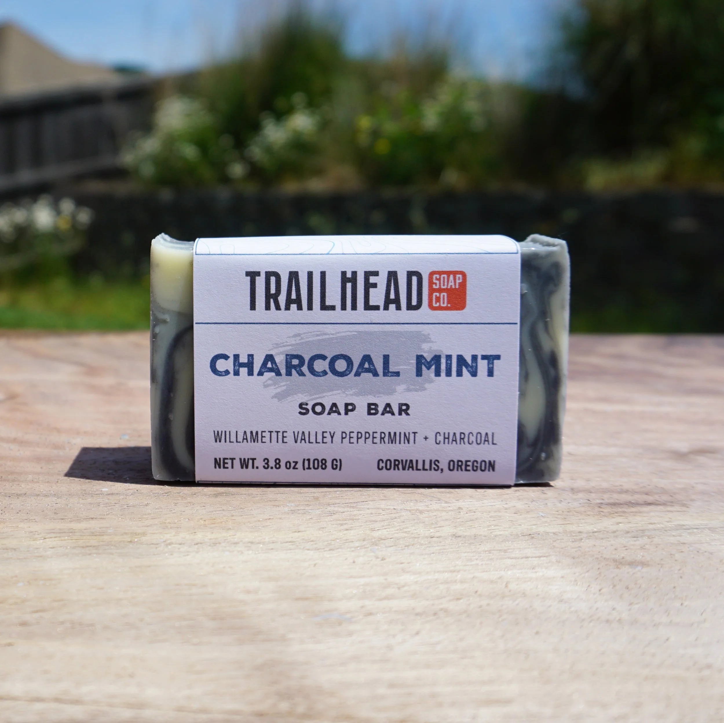 Charcoal mint soap bar outdoors on wooden surface.