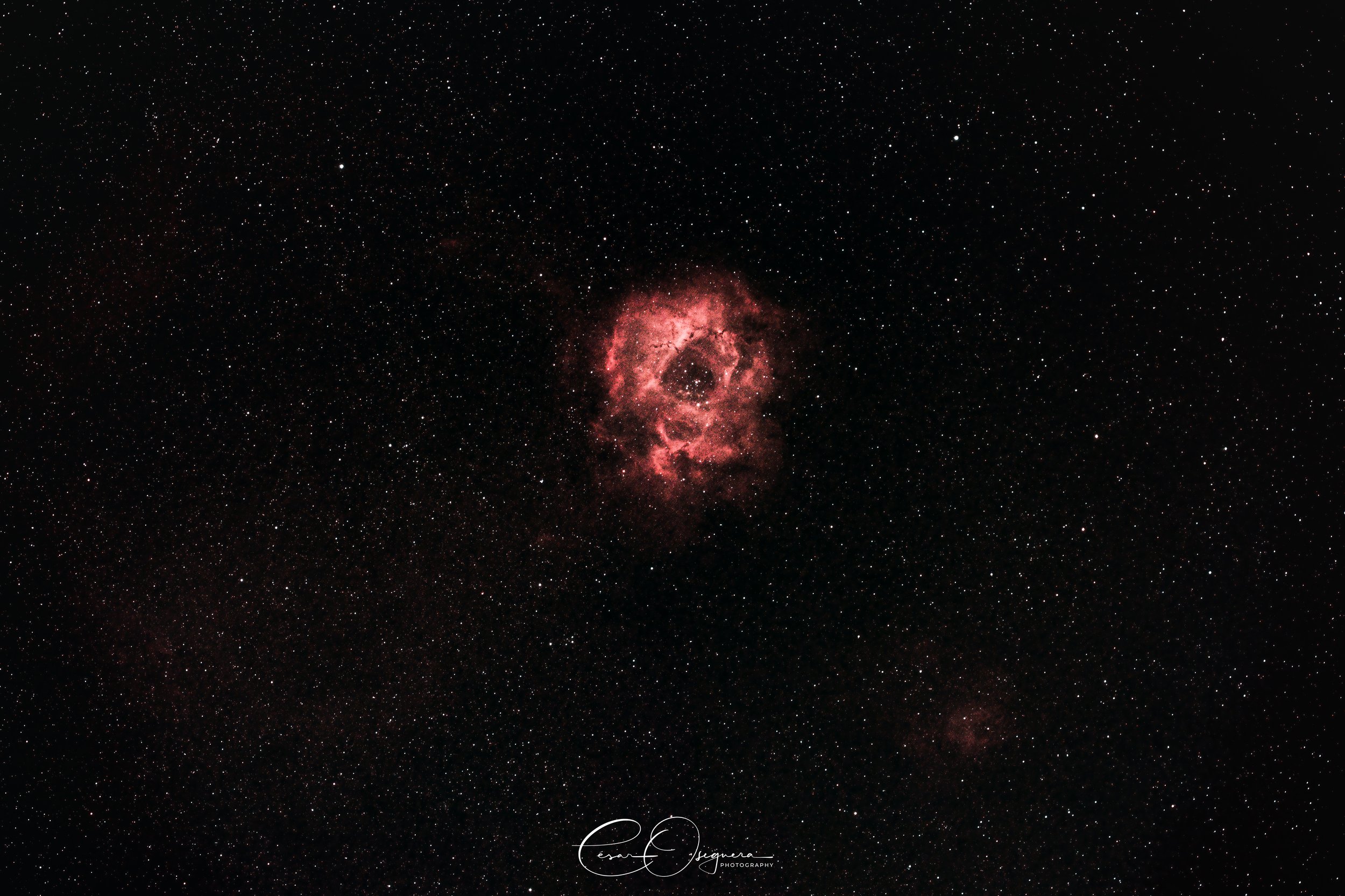Image of a red and pink nebula surrounded by numerous stars in space.