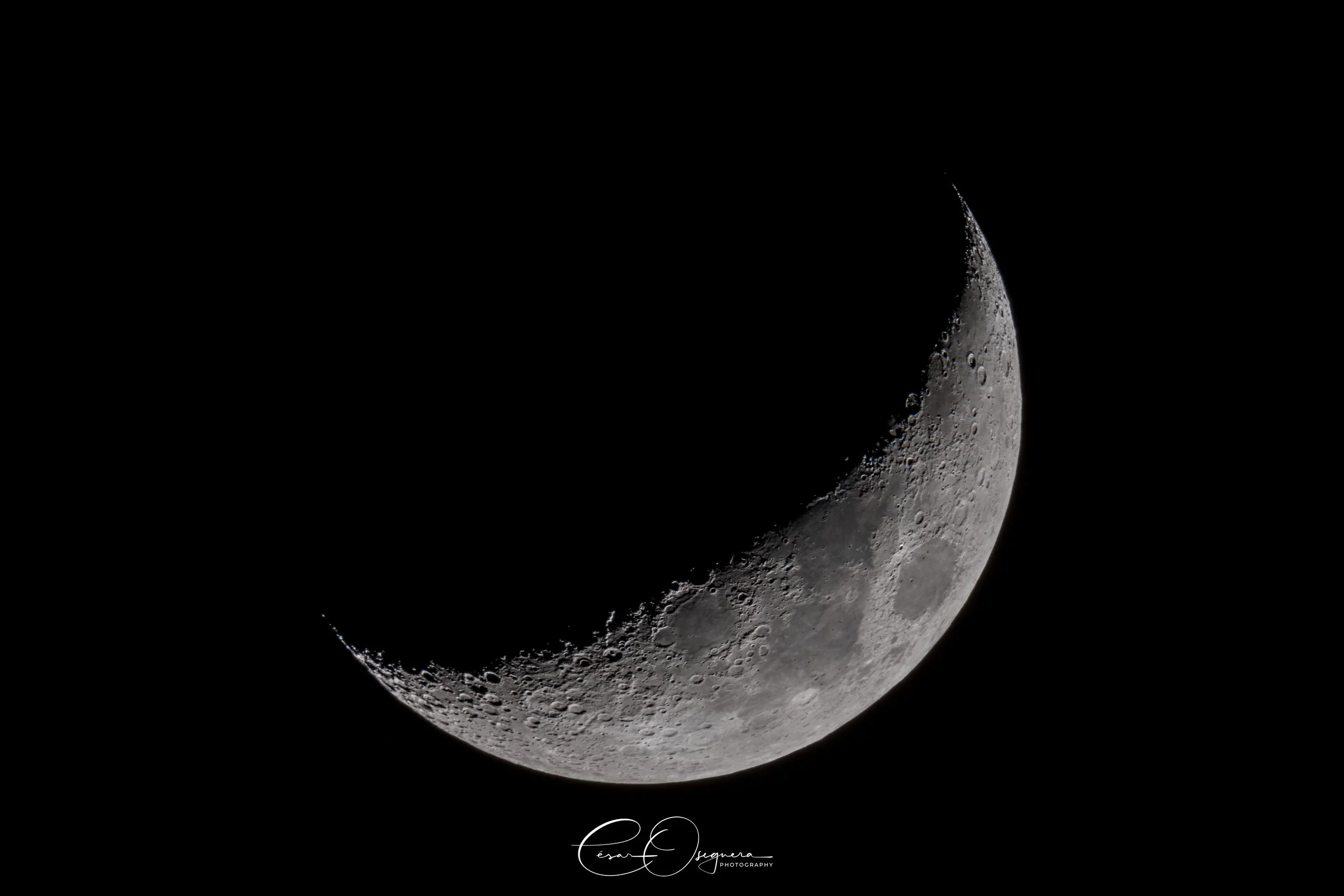 Close-up of a crescent moon showing craters and surface details against a black sky.
