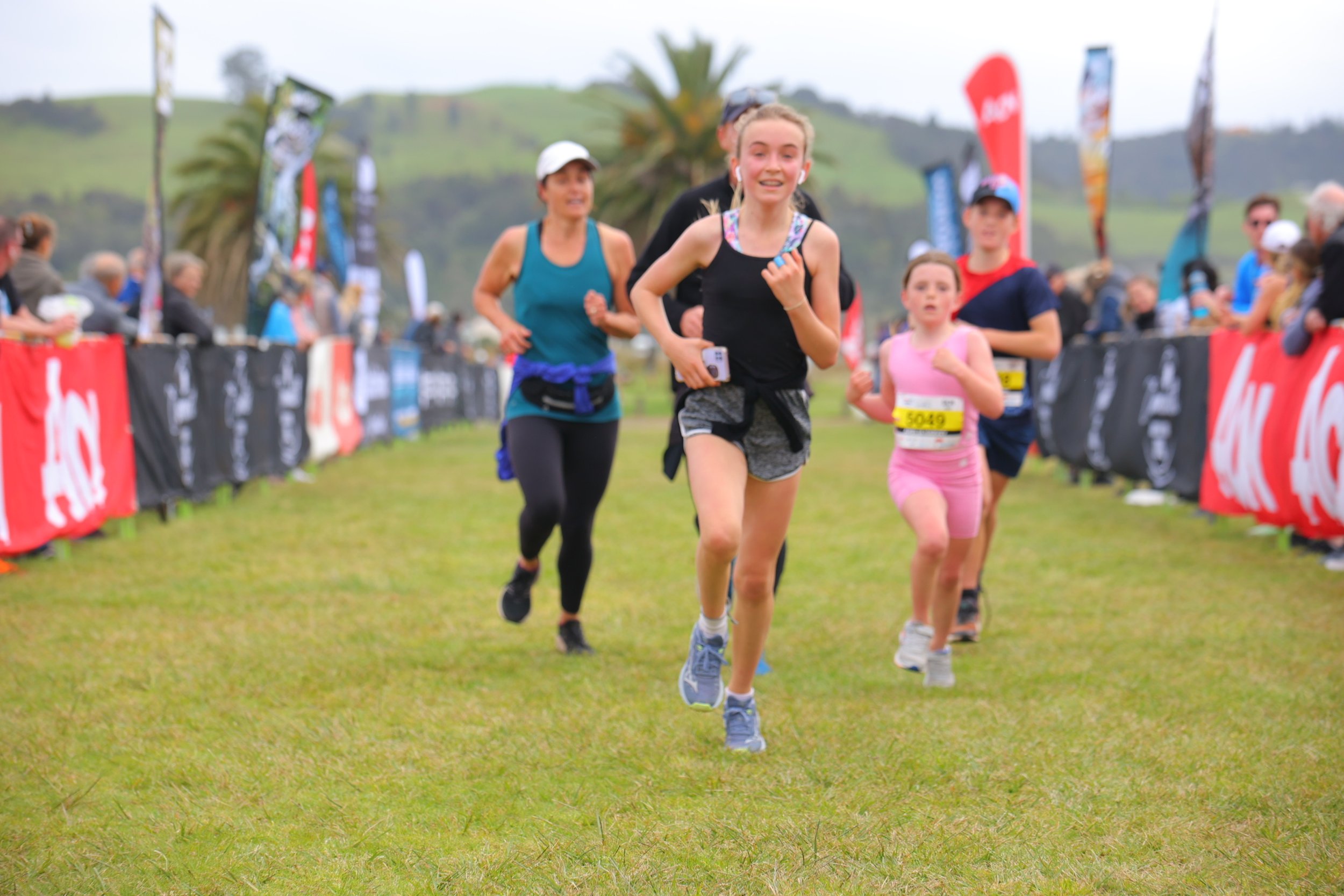 Group of runners participating in an outdoor race on a grassy field.