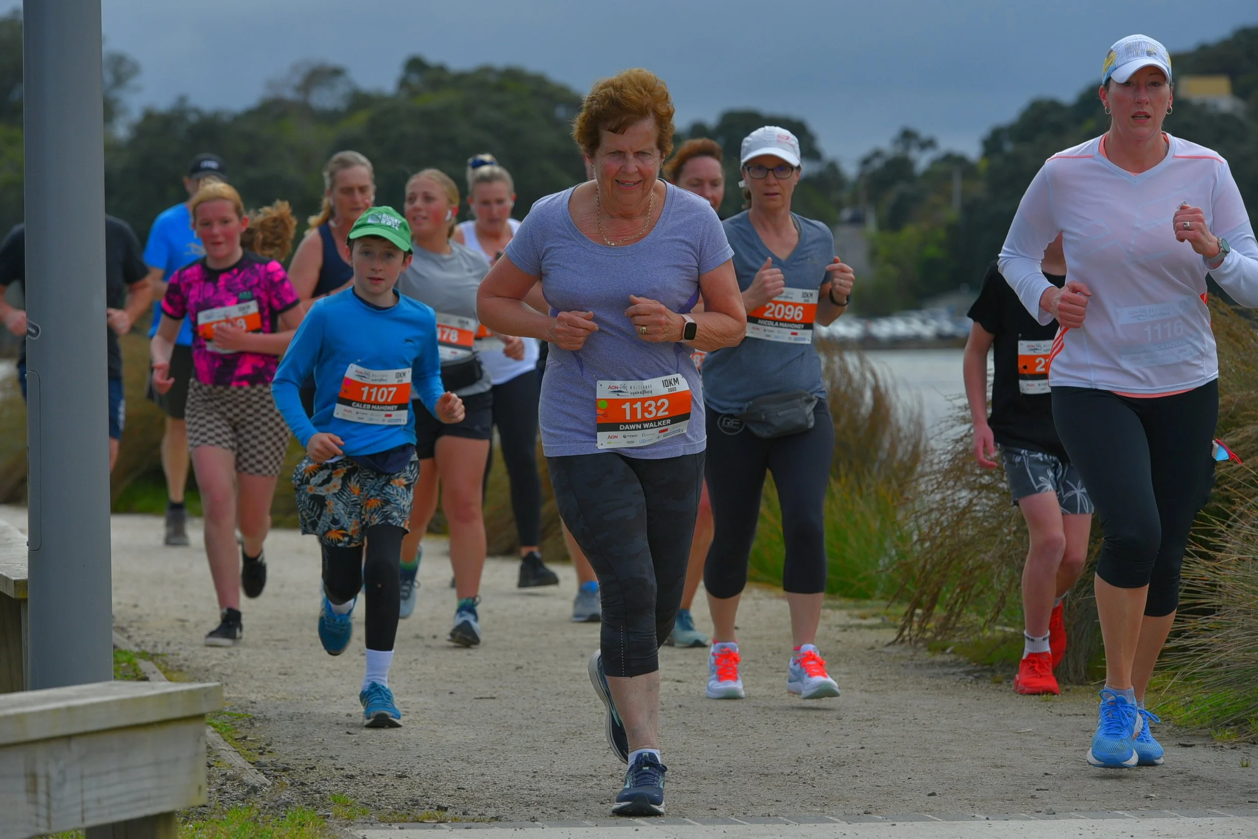 Group of people running in a race on a scenic outdoor path.