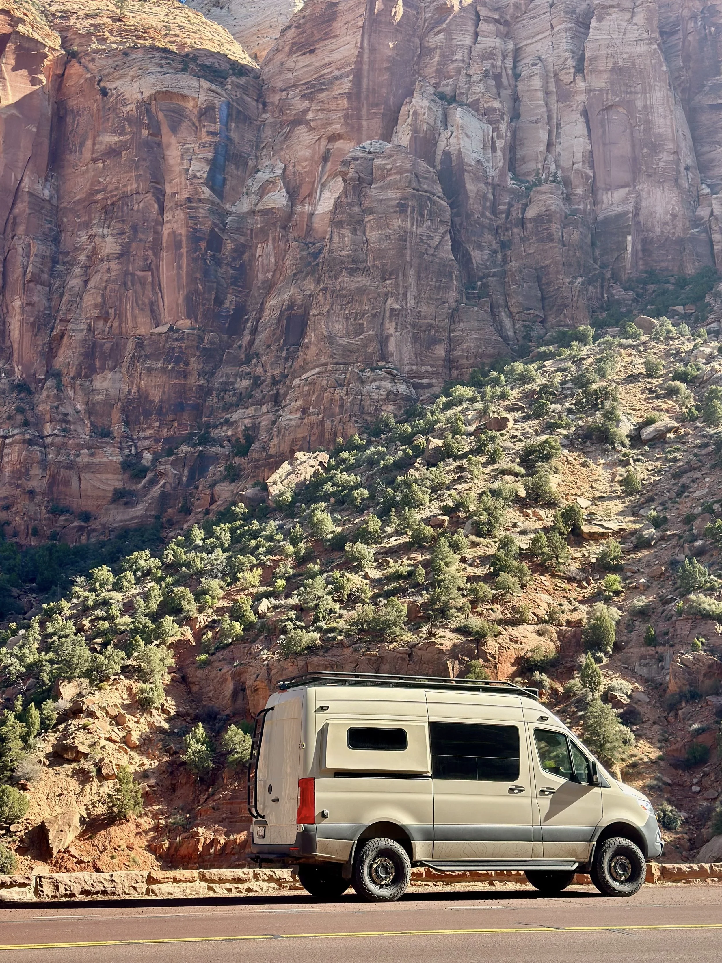 Camper van parked in front of rocky canyon landscape with vegetation