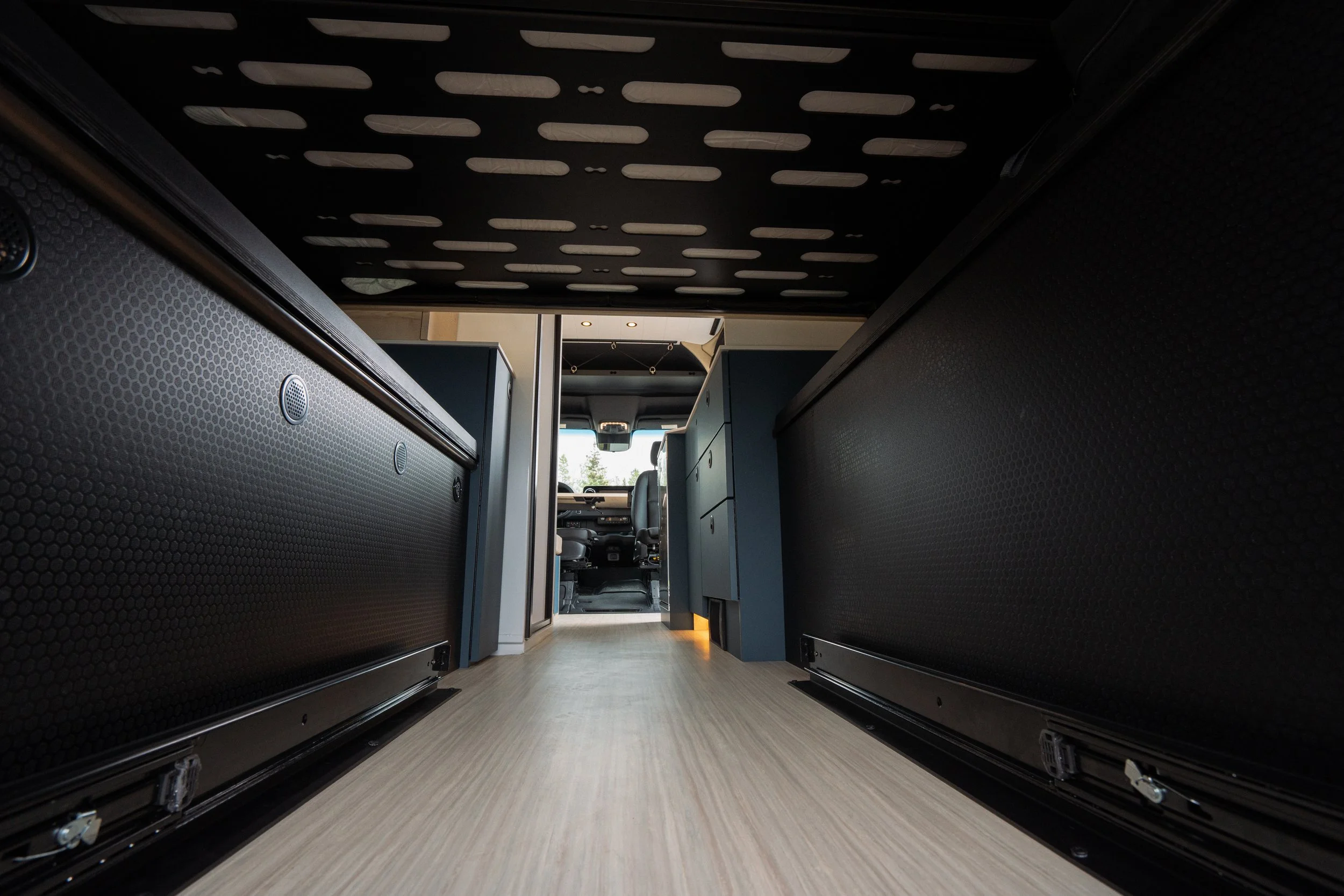 View from inside a vehicle, looking towards the front with the driver’s seat visible, a partition, and storage cabinets or cubbies on either side.