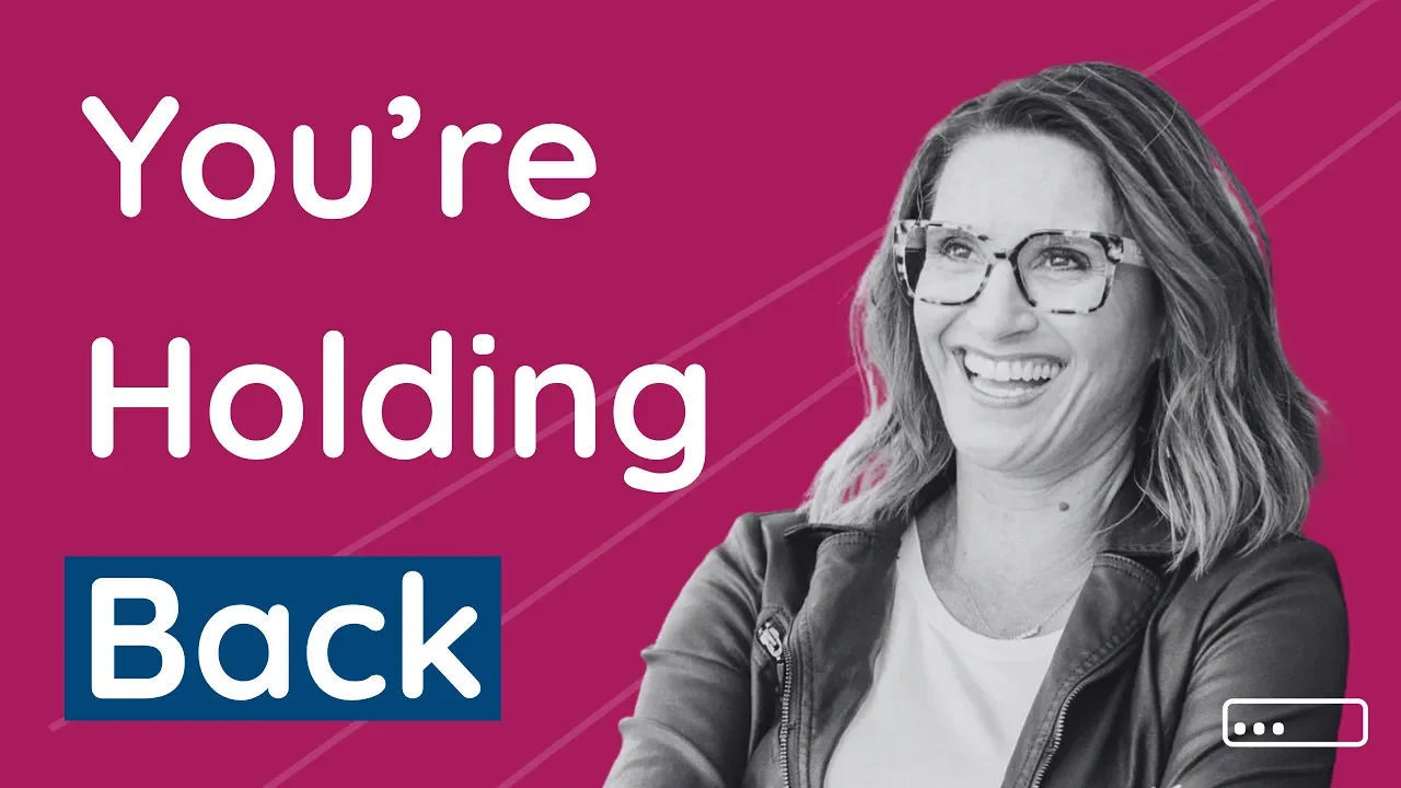 A woman with shoulder-length hair, glasses, and a leather jacket smiling against a pink background with diagonal lines. Text on the image reads "You're Holding Back" with the word "Back" highlighted in a dark blue box.