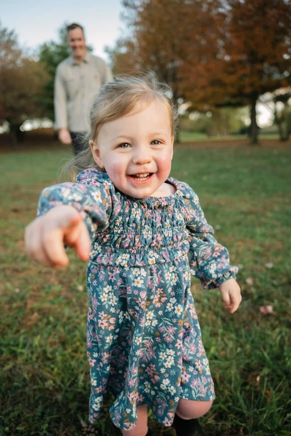 Toddler running and smiling during a fall family photo session