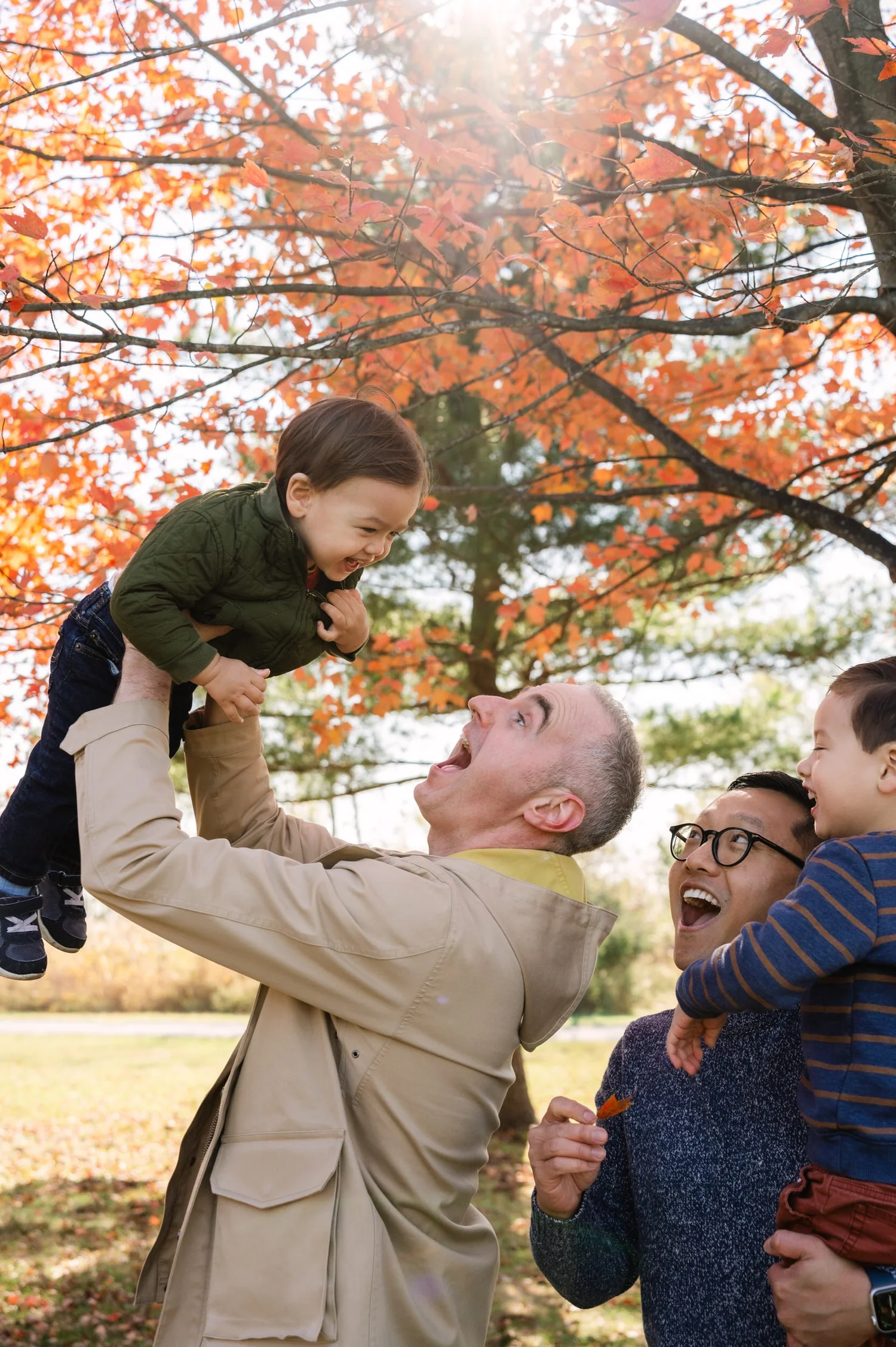 Two fathers playing with their children during a fall family session