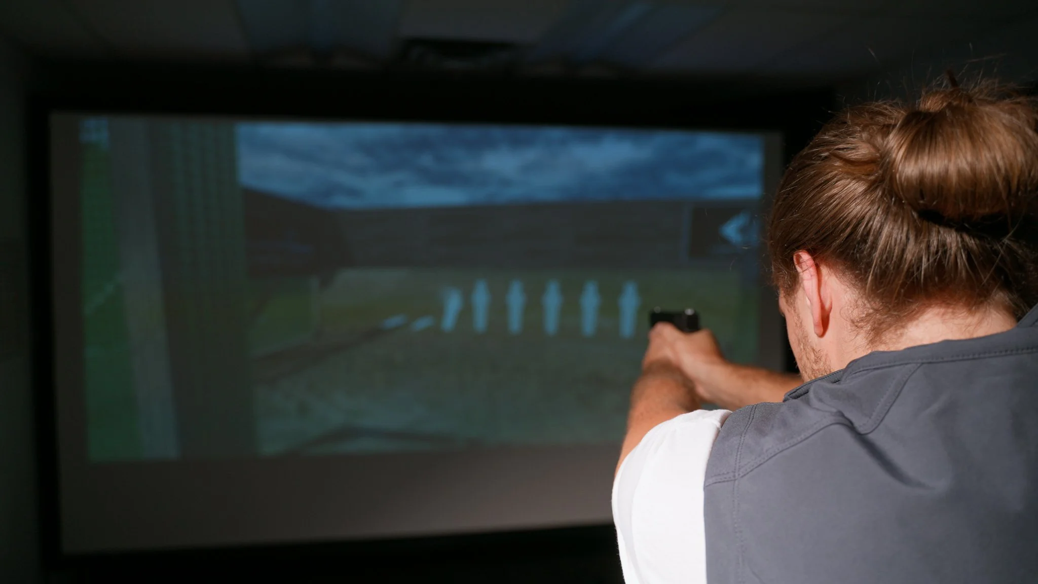 Person aiming at moving target silhouettes during shooting simulator session at LPMC