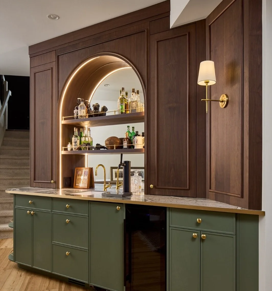 This space started as an unused wall with so much potential. This basement was large and a drop zone for all, so we transformed it into a custom bar that feels like it was always meant to be here.

Rich walnut millwork, an arched mirrored backdrop, c