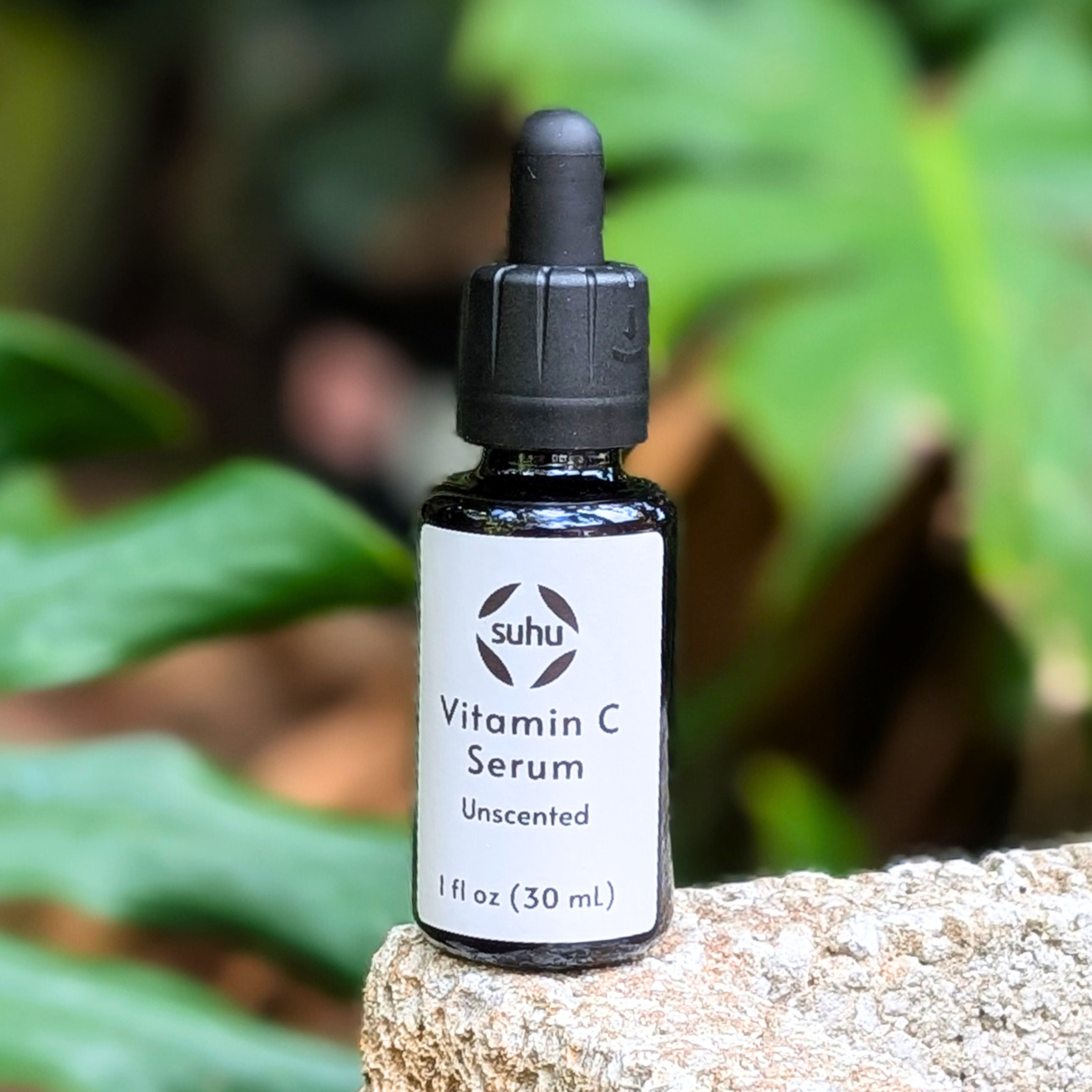 Vitamin C black bottle with unscented label. The bottle is sitting outside in front of plants.