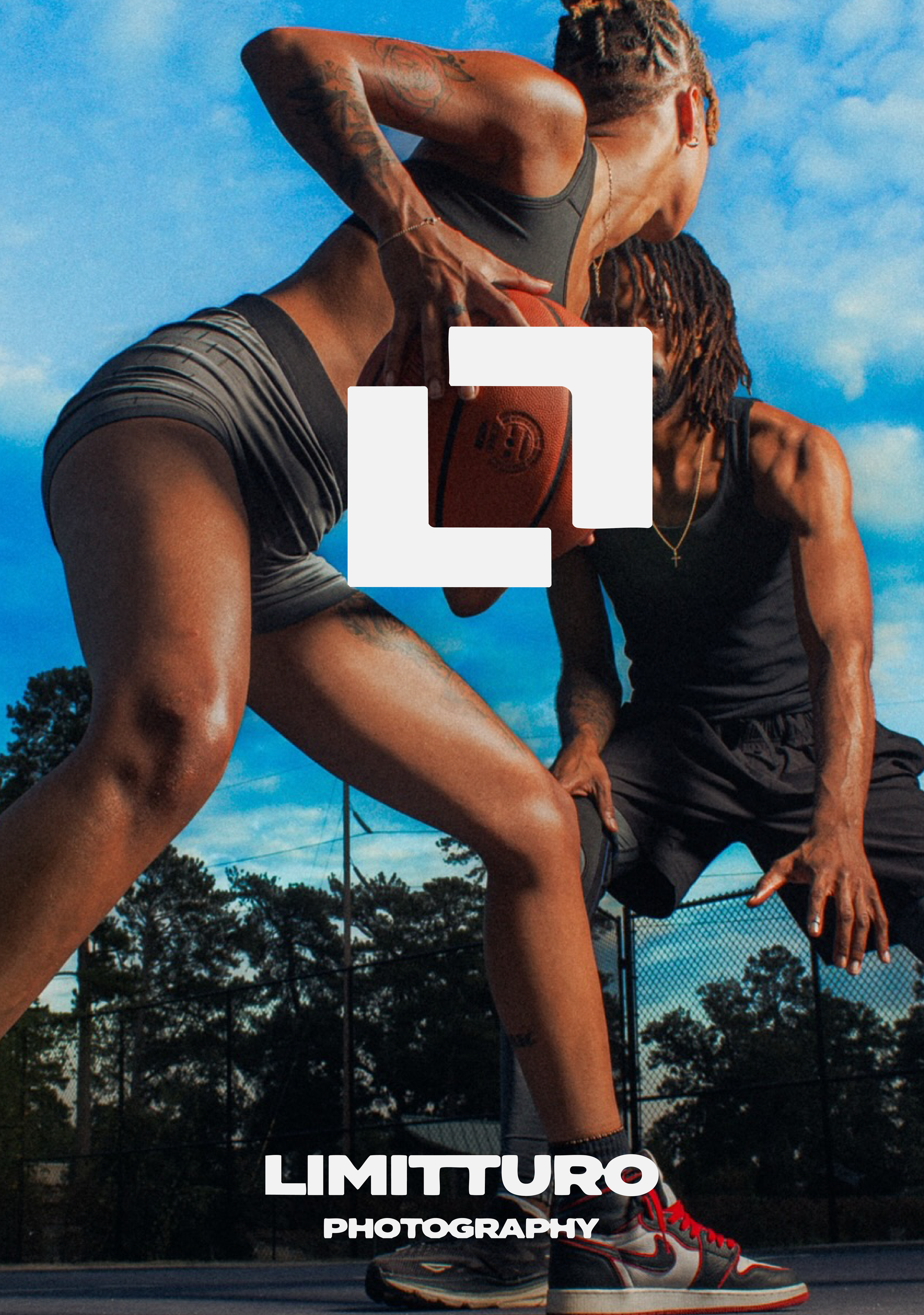 Two women playing basketball outdoors under a blue sky with clouds, one holding the ball and the other in a defensive stance.