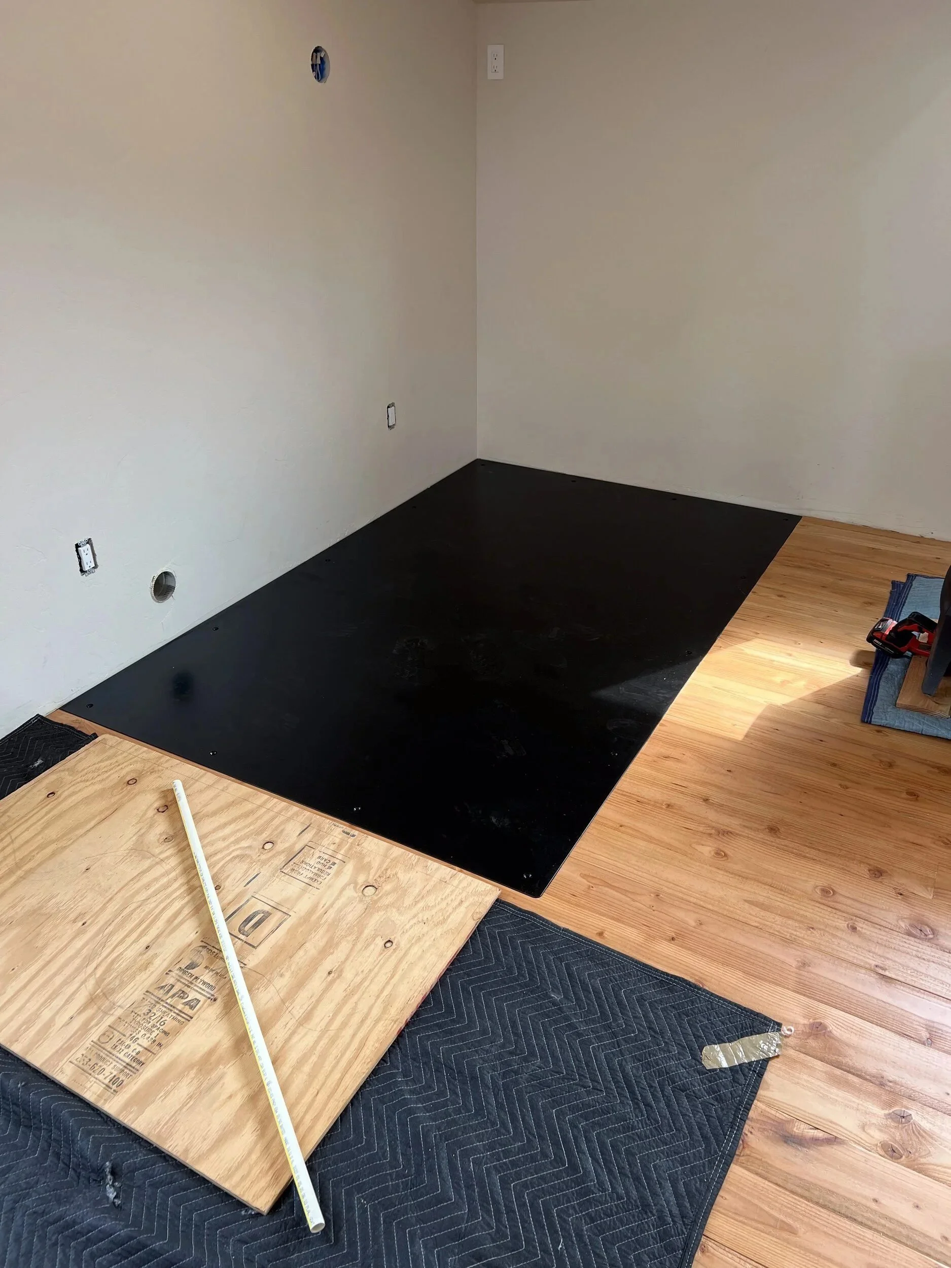 Steel hearth plate recessed into the floor so its surface sits flush with the surrounding wood flooring — designed and fabricated by de stijl FORMS in Hood River, Oregon.