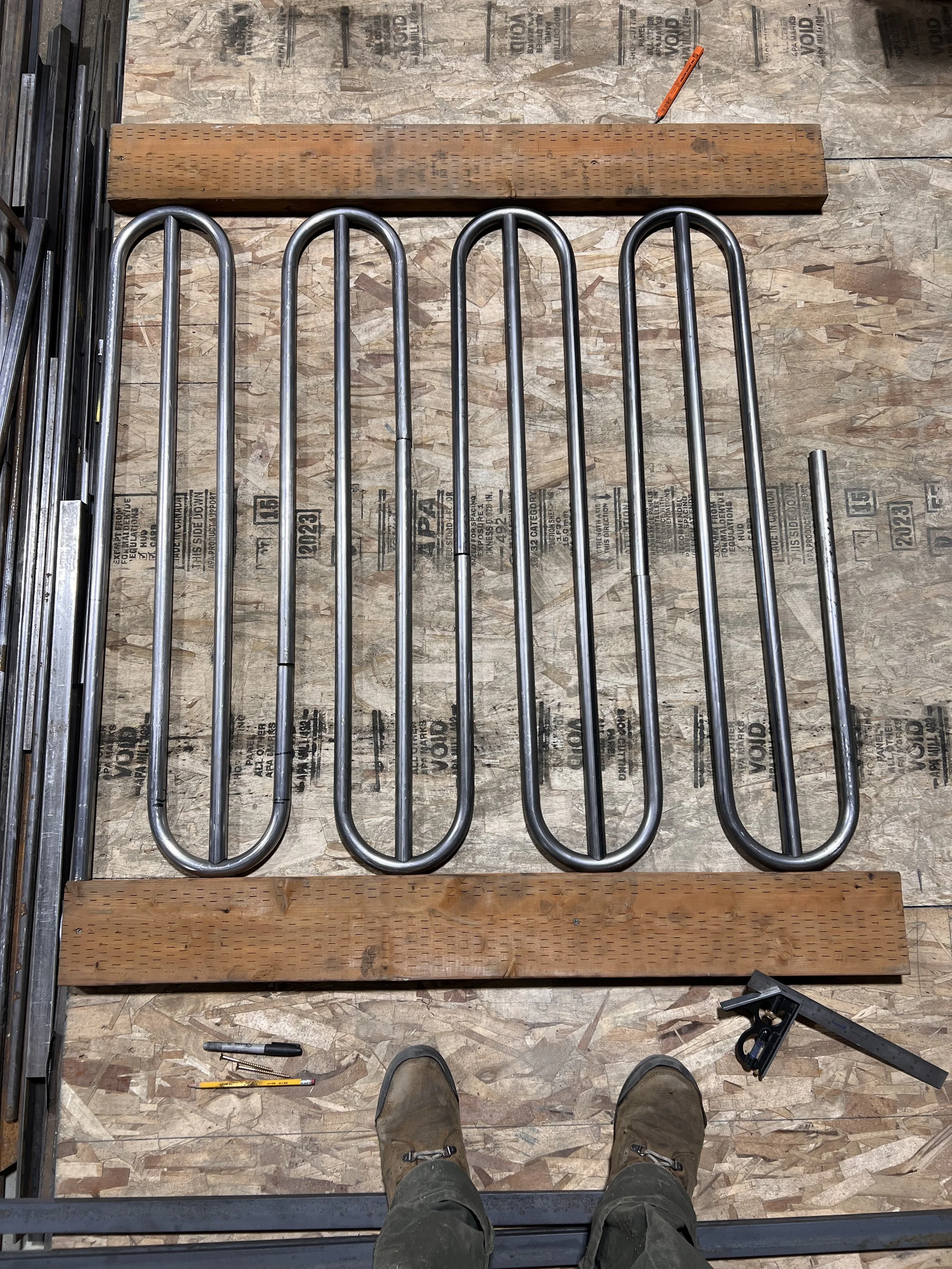 Hand-bent steel tube components laid out during fabrication of the custom interlocking railing for the Love & Hominy parklet in Hood River, Oregon.