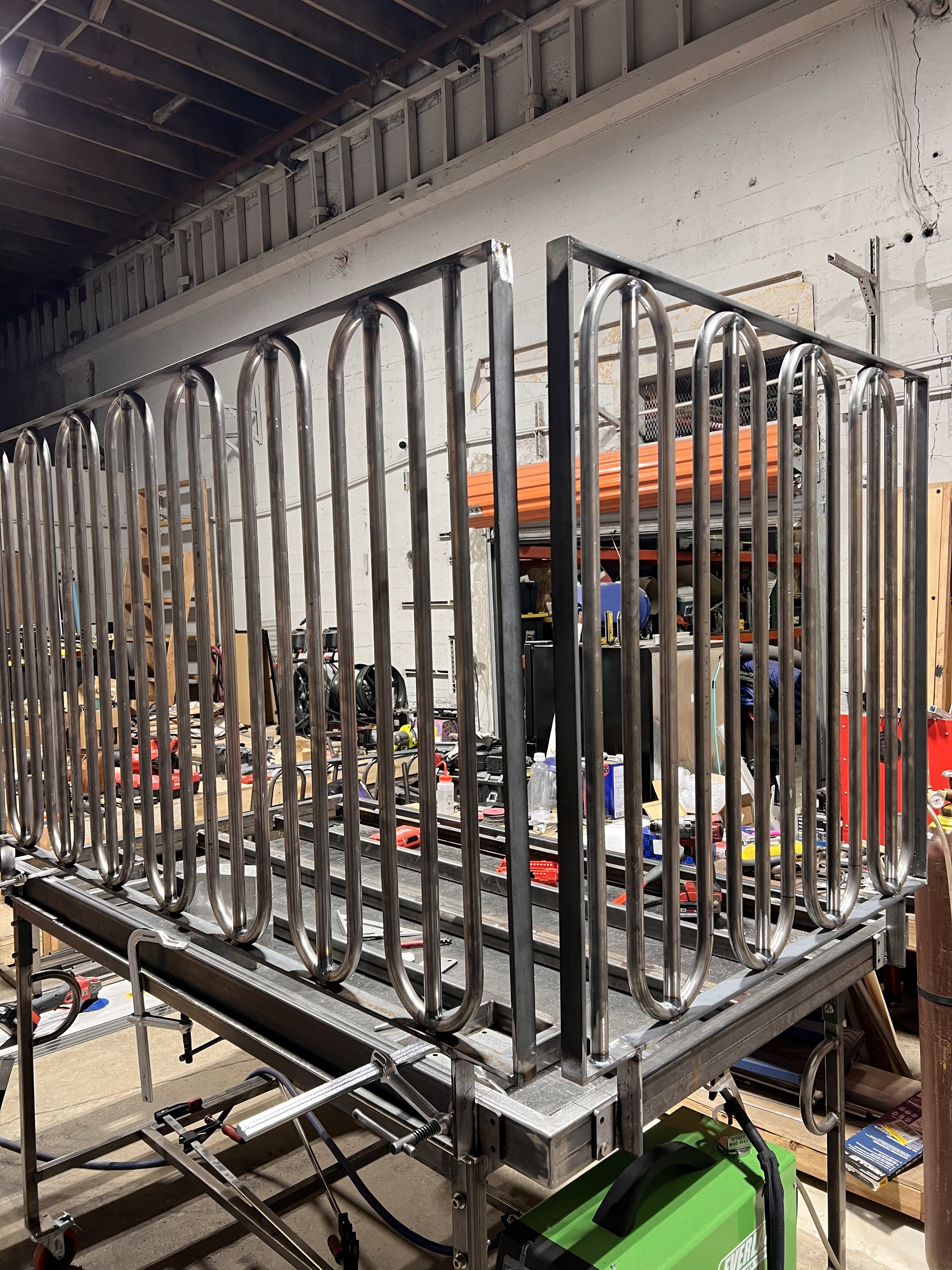 Raw-steel assembly of the Love & Hominy parklet showing separate railing panels, structural framing, and modular connections during fabrication by de stijl FORMS.