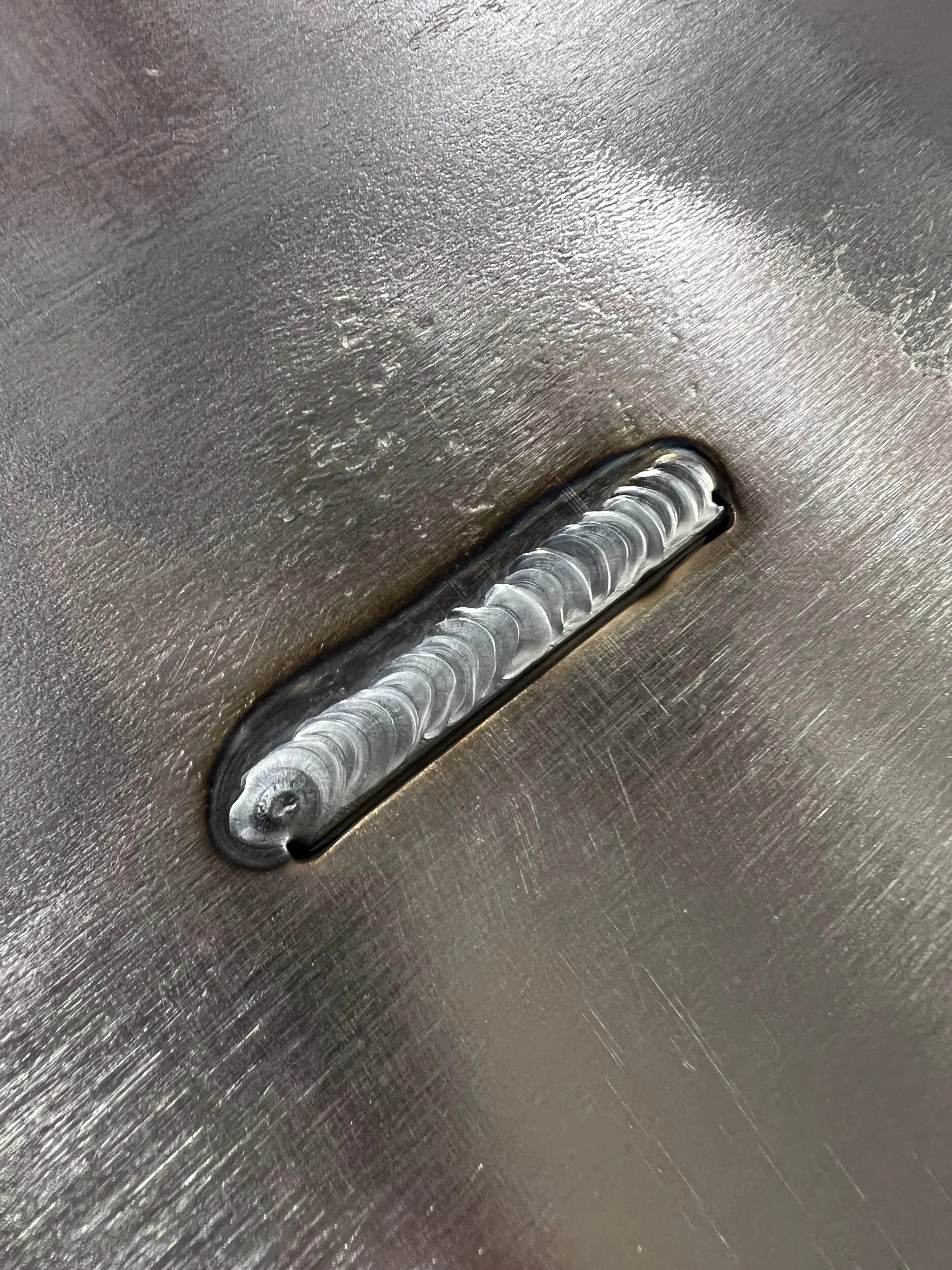 Steel tab plug welded through its slot, ready to be ground flush on a custom firewood box — designed and fabricated by de stijl FORMS in Hood River, Oregon.