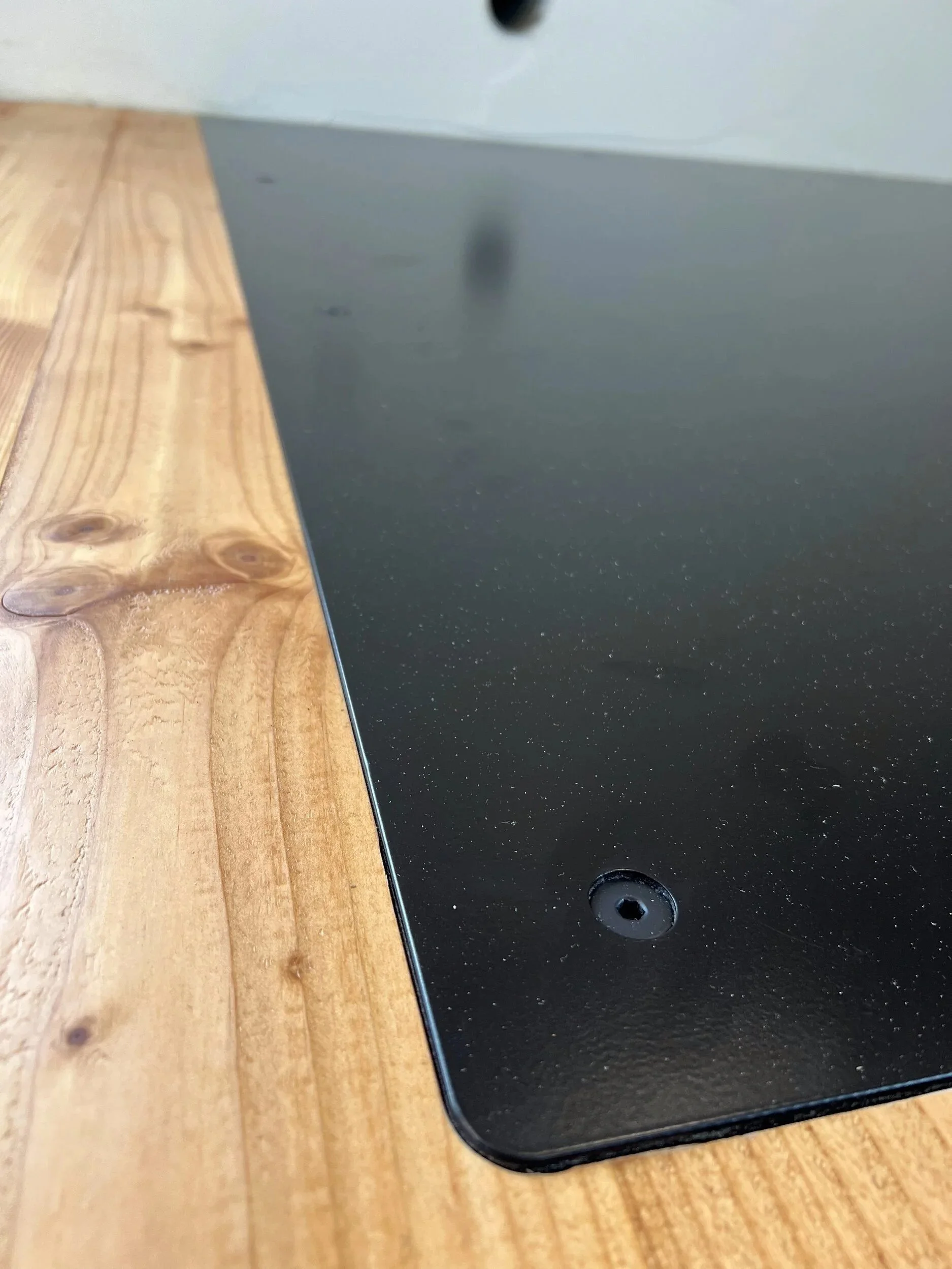 Edge detail of a steel hearth plate meeting the wood floor flush, with no trim or transition strip — designed and fabricated by de stijl FORMS in Hood River, Oregon.
