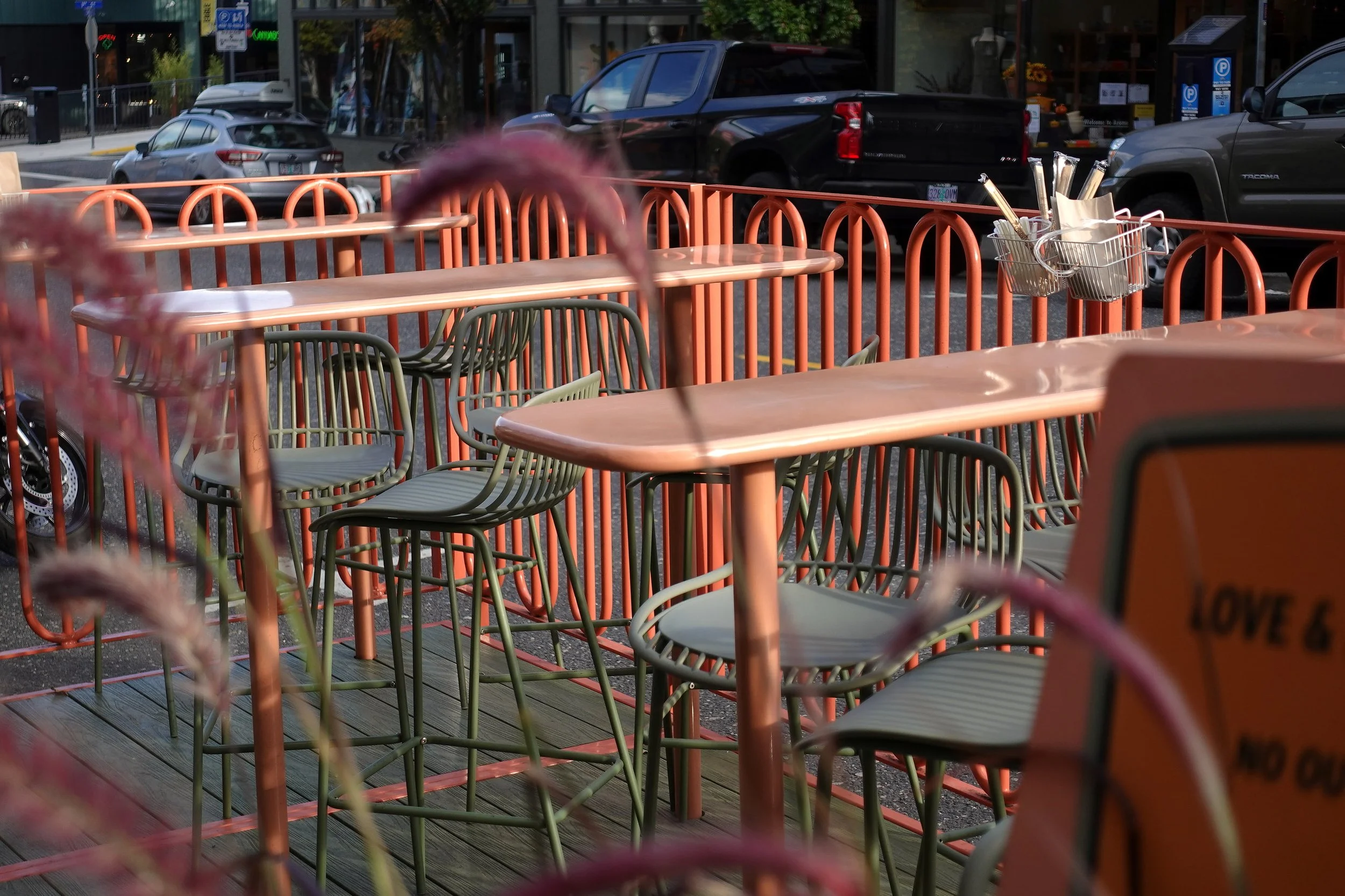 Finished Love & Hominy parklet in Hood River, Oregon, showing the integrated steel tables, seating area, custom railing, and green composite decking designed and fabricated by de stijl FORMS.