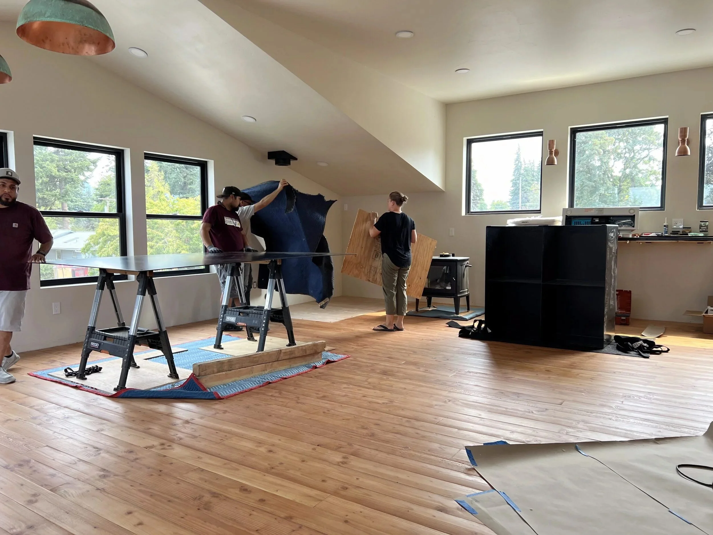 Installing a custom steel firewood box in the wood-stove corner of a second-floor room — designed and fabricated by de stijl FORMS in Hood River, Oregon.