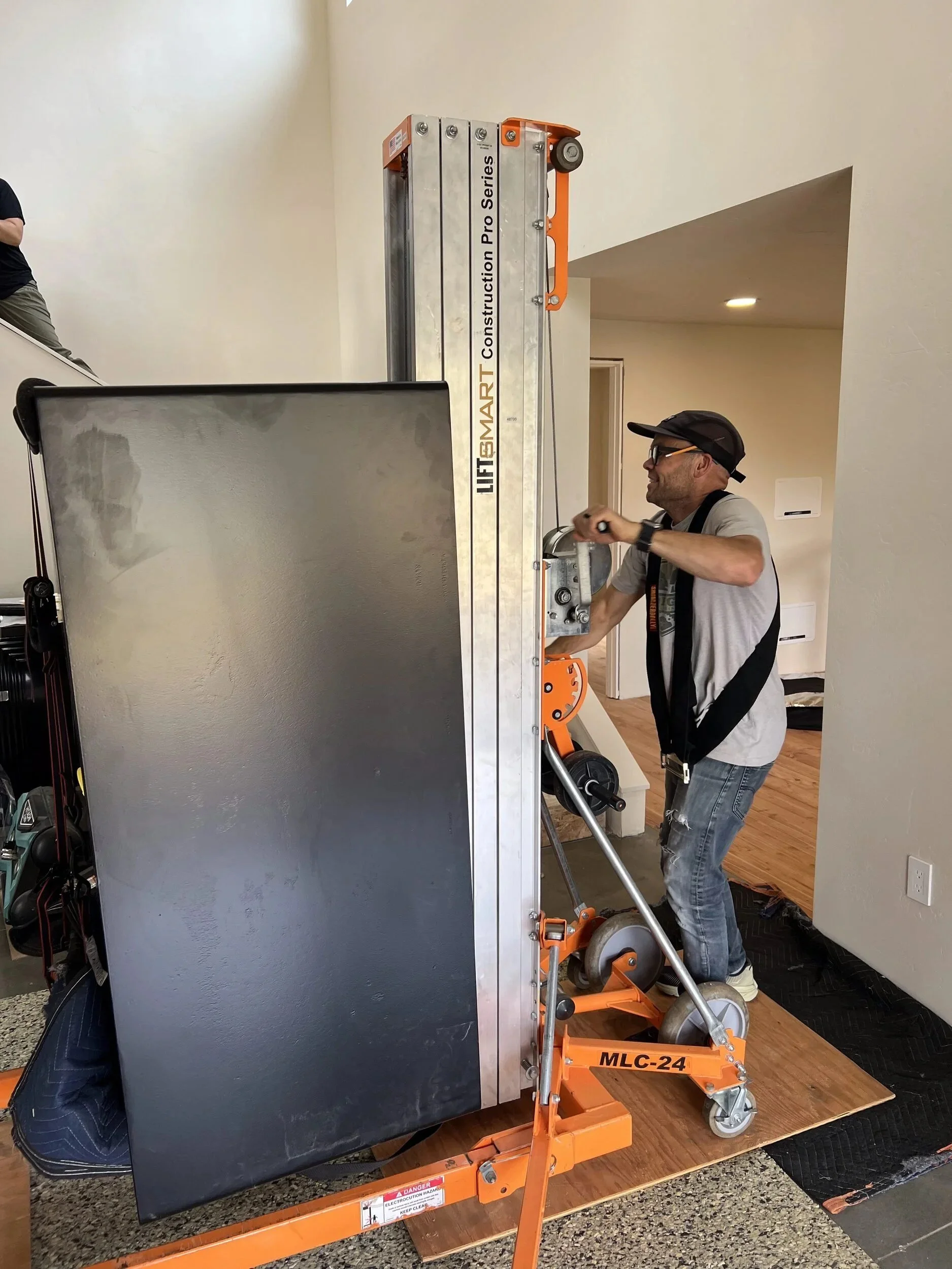 Installers carrying a heavy steel hearth plate into a Hood River home — designed and fabricated by de stijl FORMS in Hood River, Oregon.