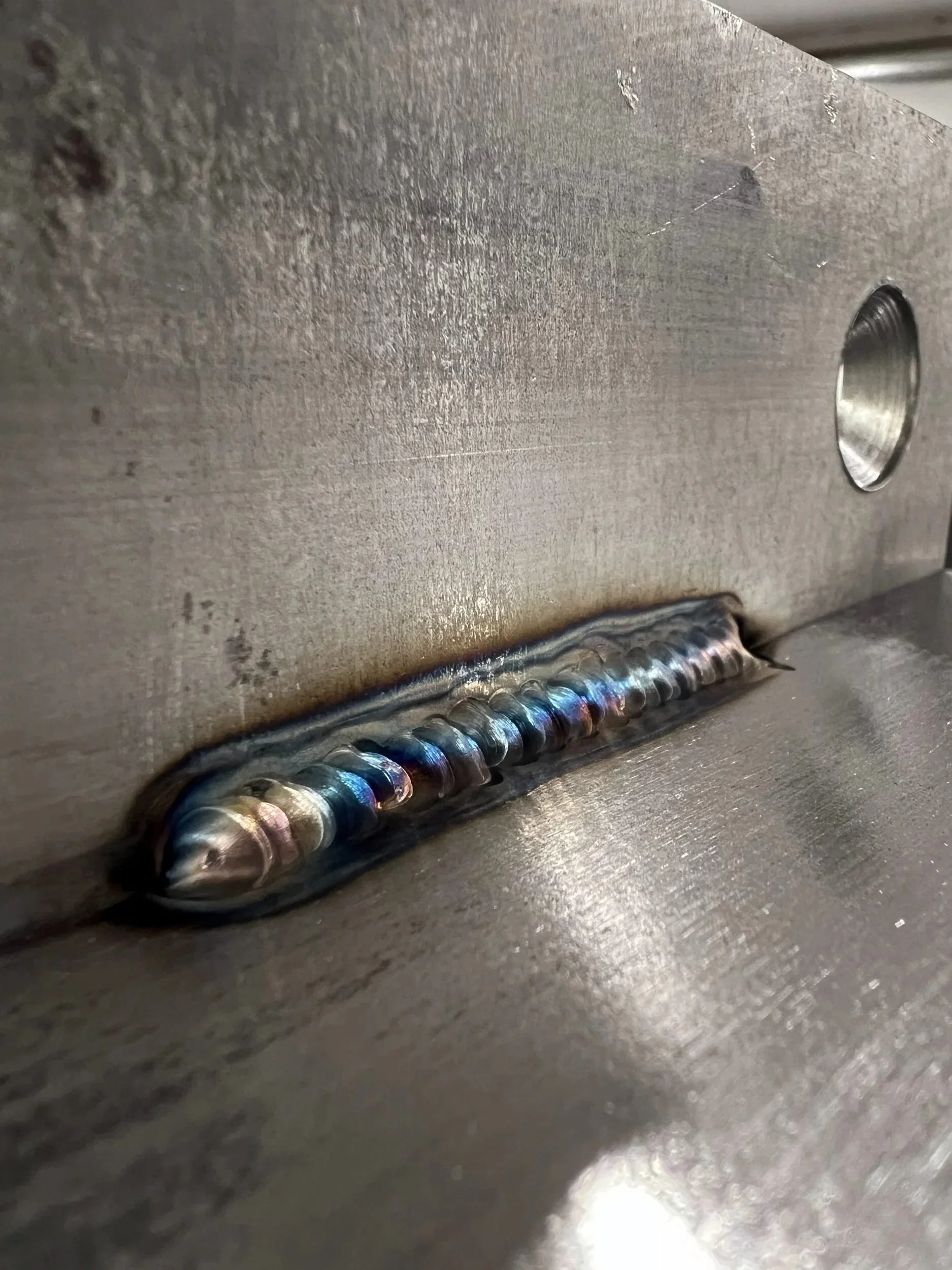 Weld detail on a steel tab-and-slot connection during fabrication of a firewood storage box — designed and fabricated by de stijl FORMS in Hood River, Oregon.