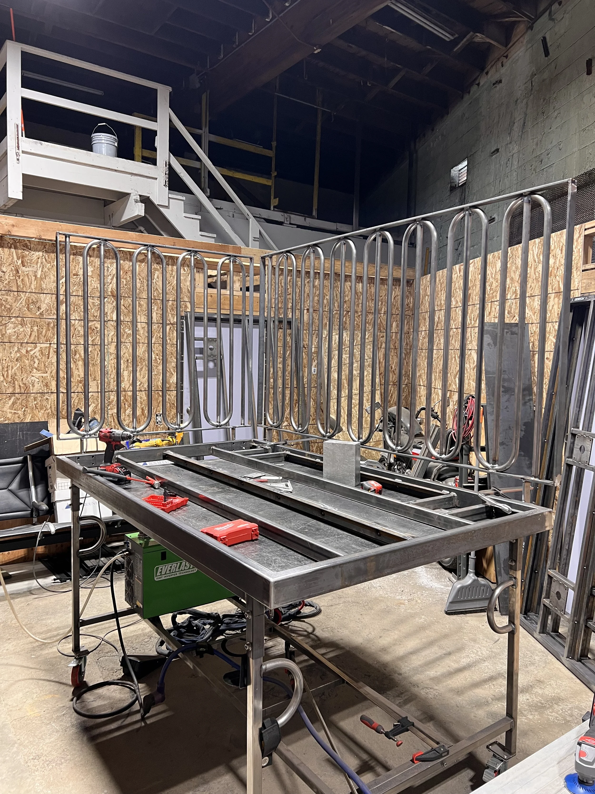Love & Hominy parklet assembled in the shop during fabrication, showing the modular steel frame and removable railing sections before decking and finishing.