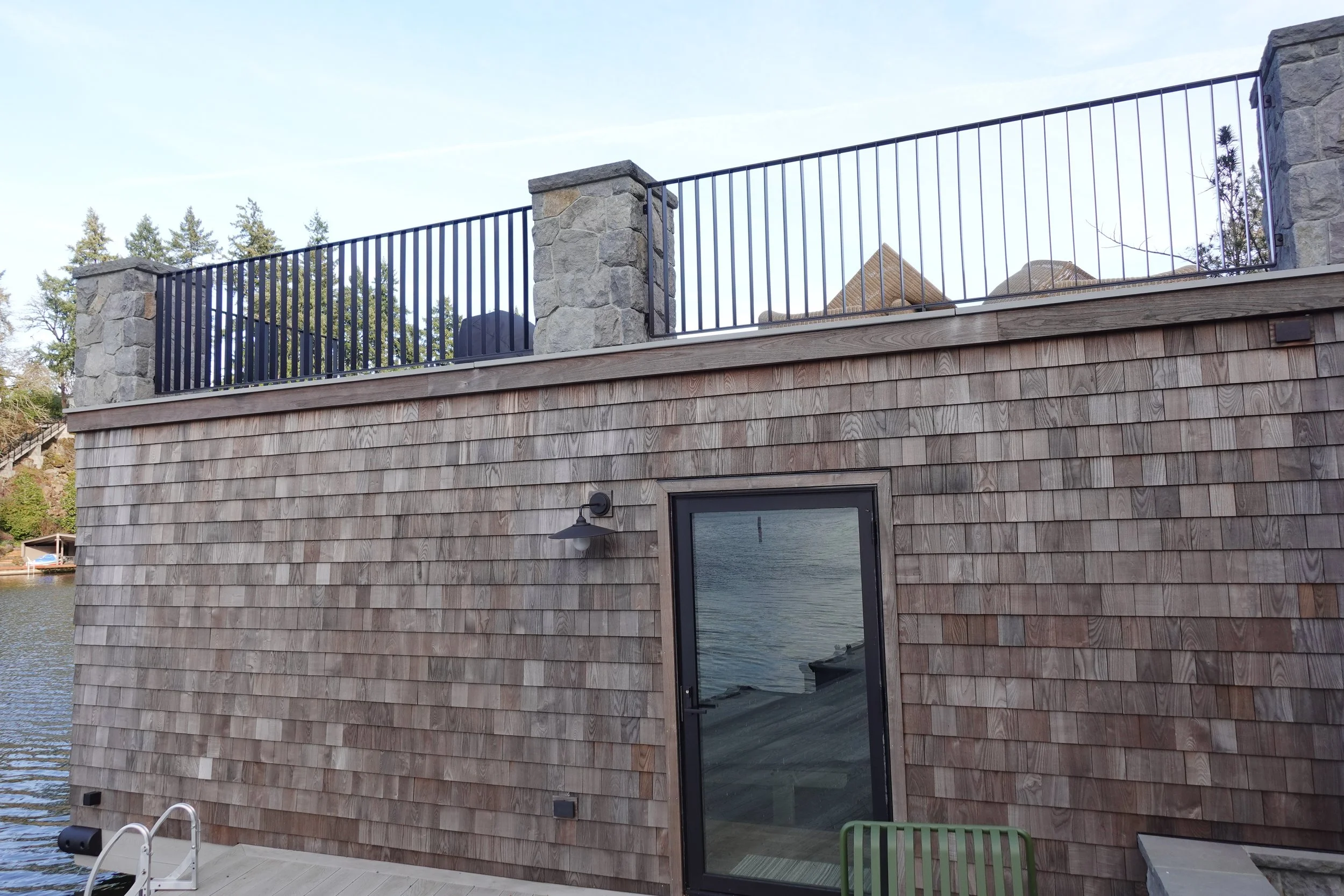 Custom black steel railing integrated with the cedar-shake boathouse at The York waterfront residence in Lake Oswego, Oregon.