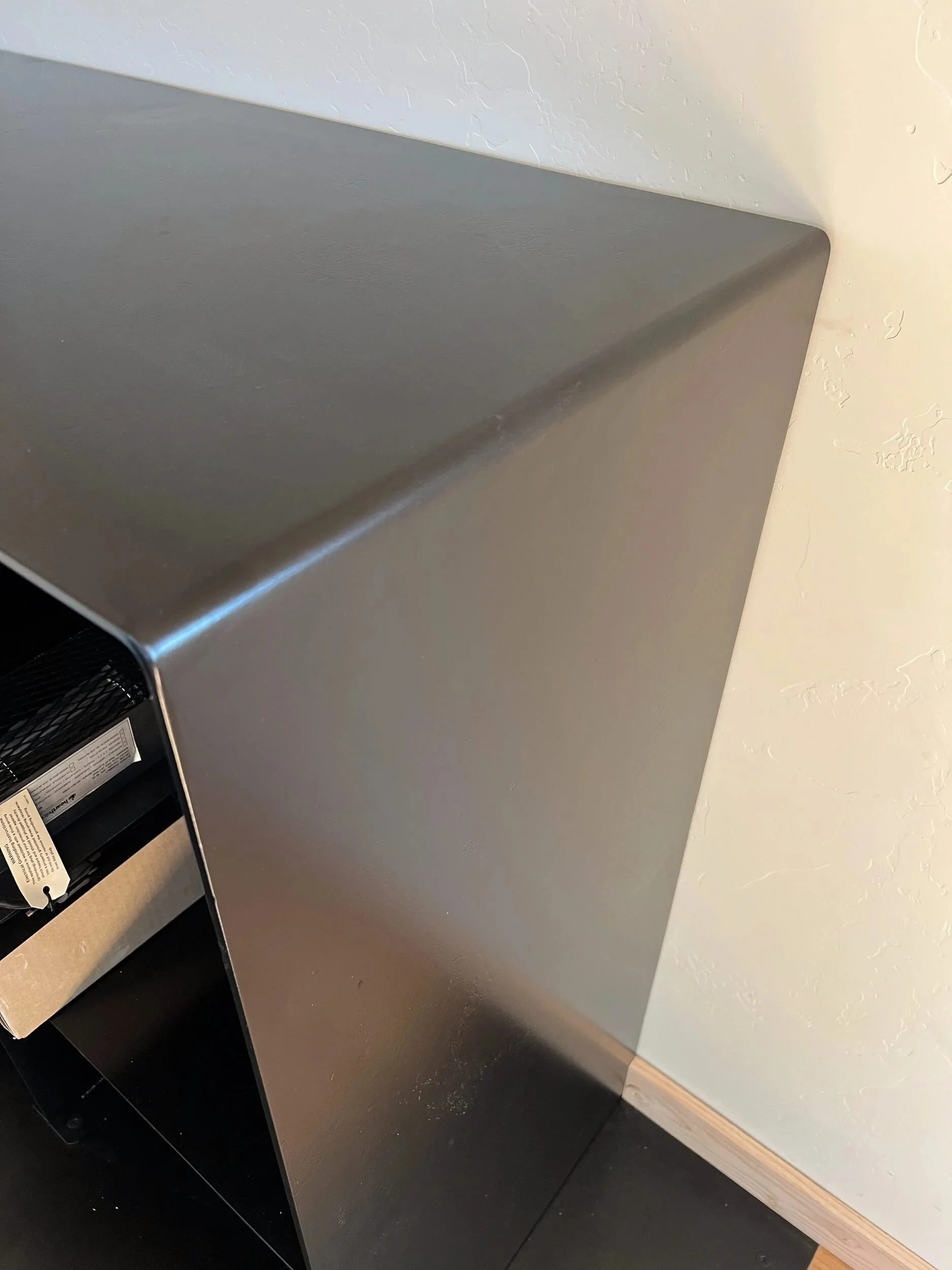 Detail of a crisp folded steel edge on a custom satin black firewood box — designed and fabricated by de stijl FORMS in Hood River, Oregon.
