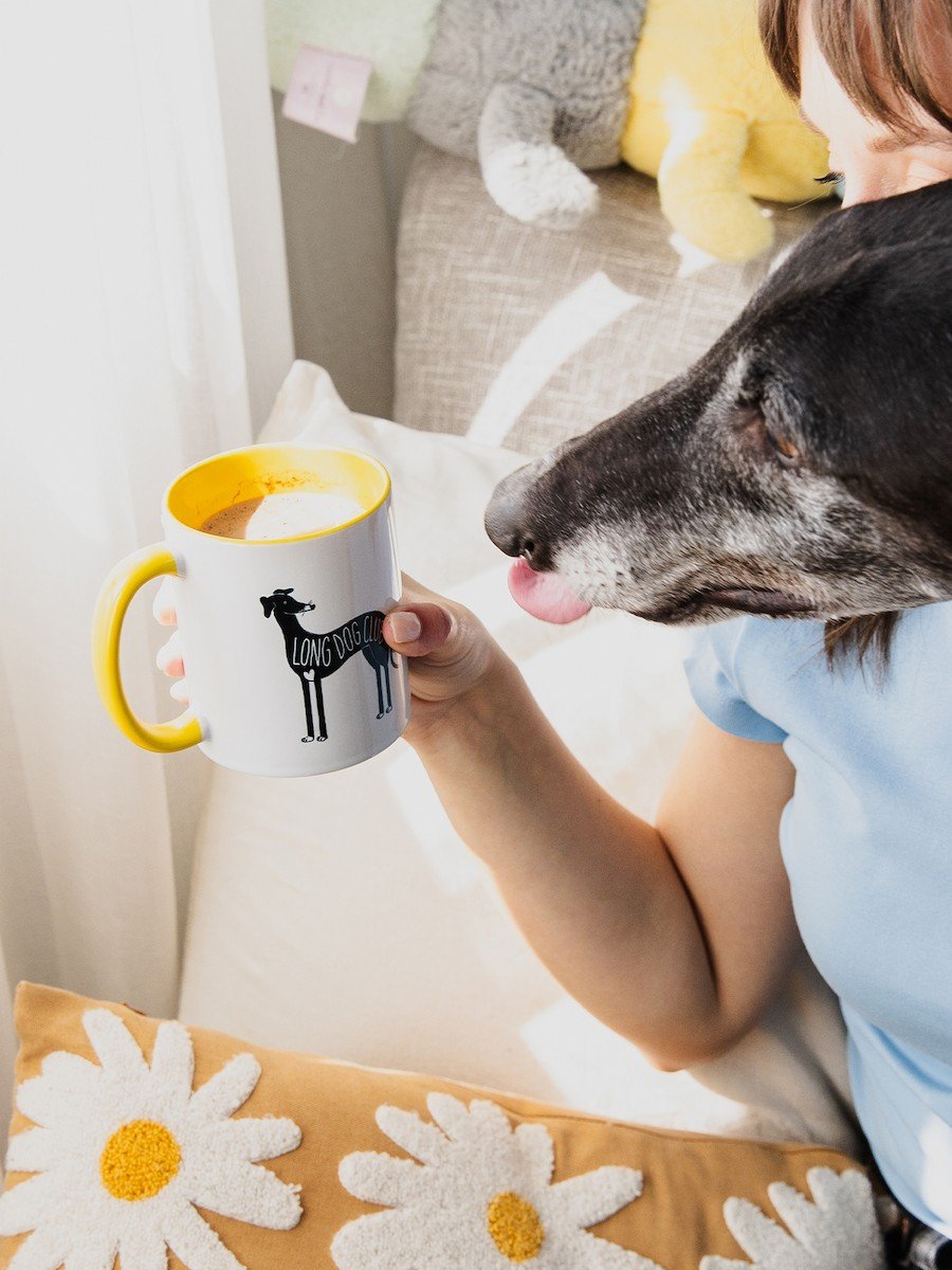 Woman holds a ceramic mug next to a greyhound, the perfect dog gift idea