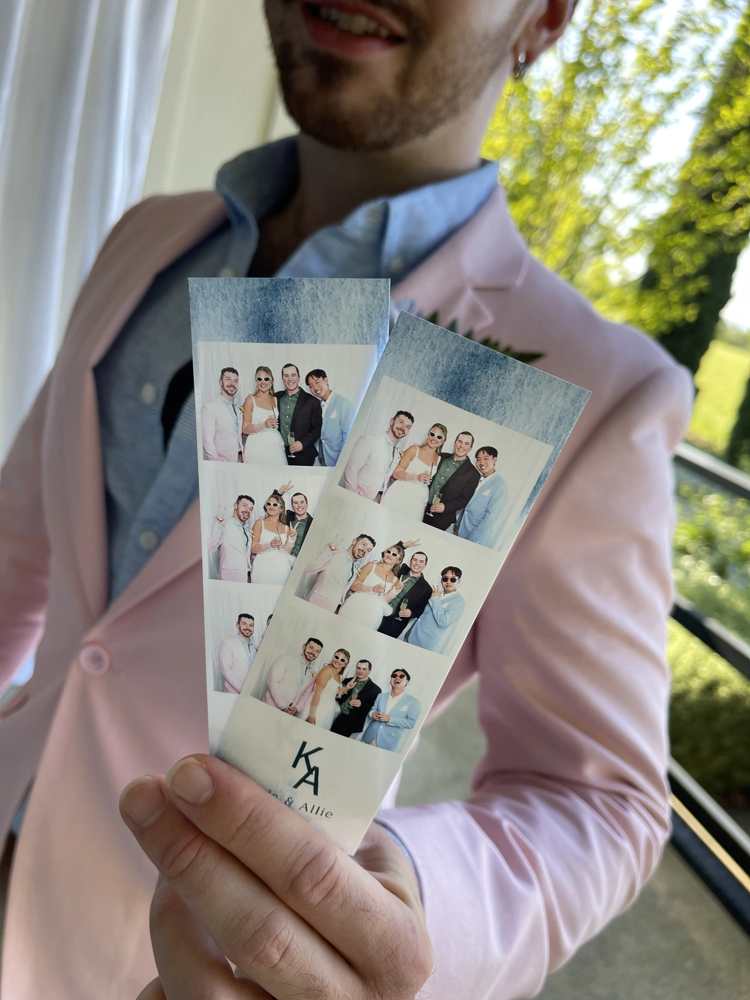 Wedding guest holding personalized printed photo booth strips featuring group photographs