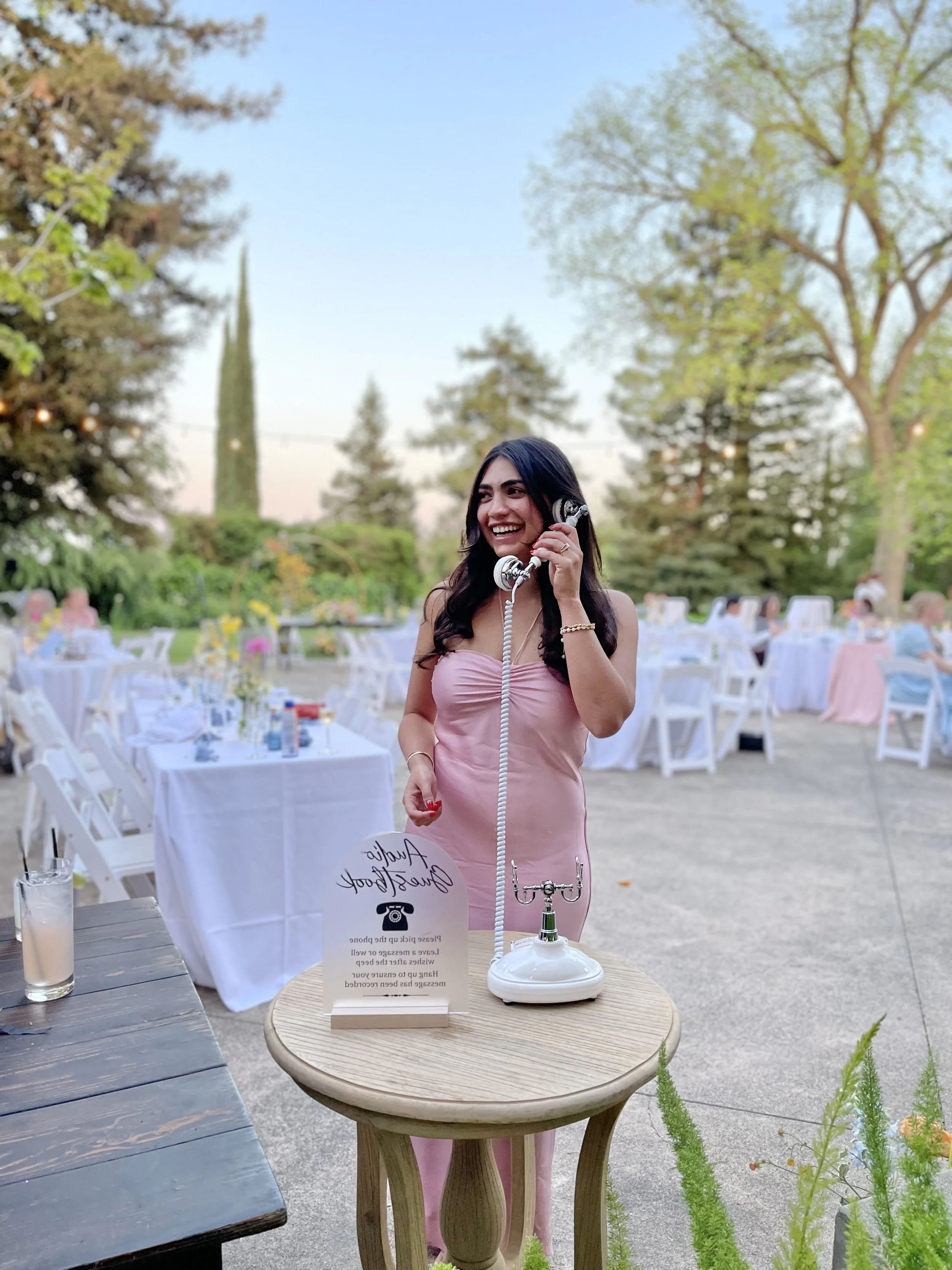 A wedding guest smiling while leaving a voice message using Creative Corner Rentals Audio Guest Book