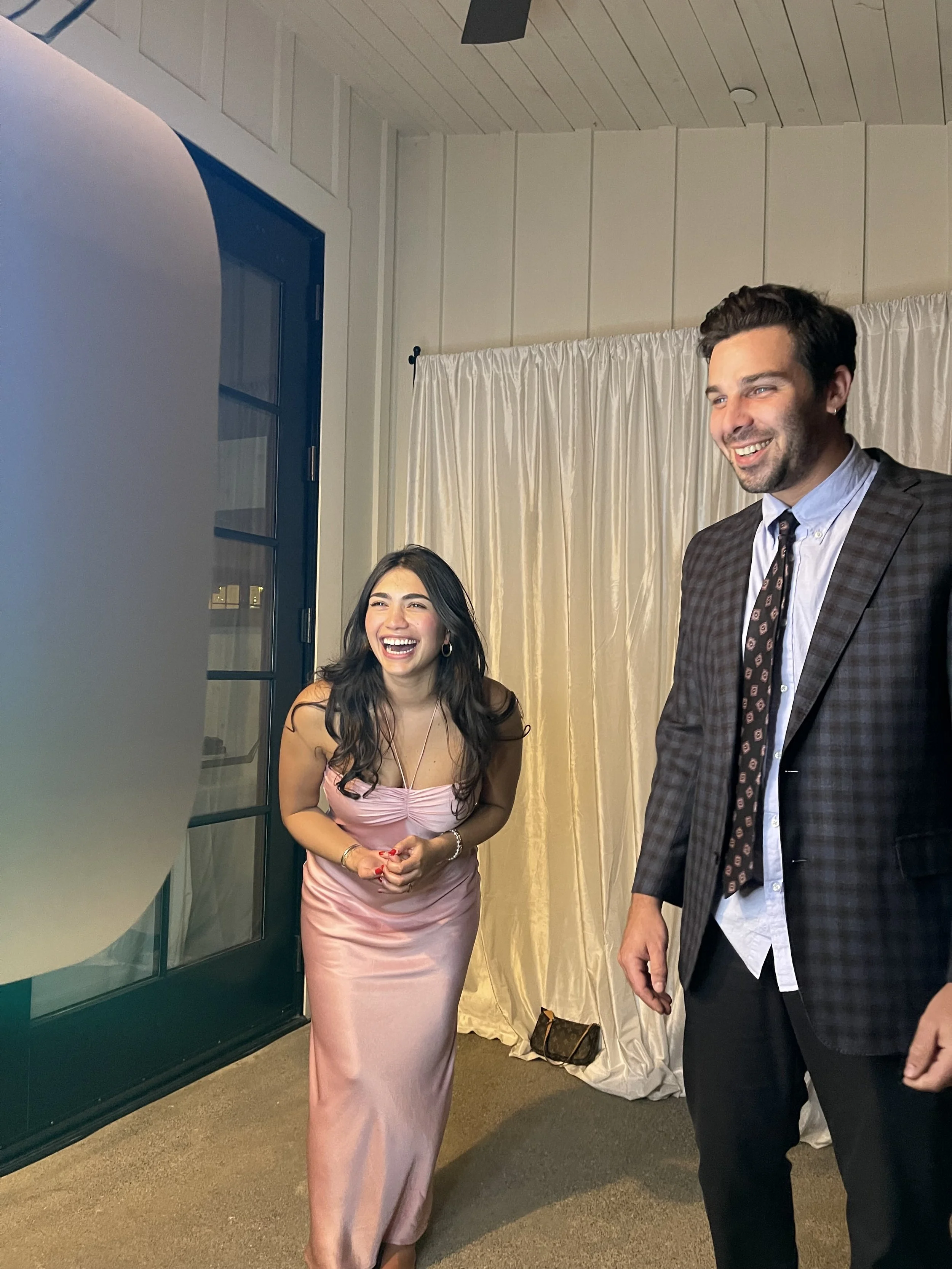 Two wedding guests laughing and smiling while enjoying a photo booth experience