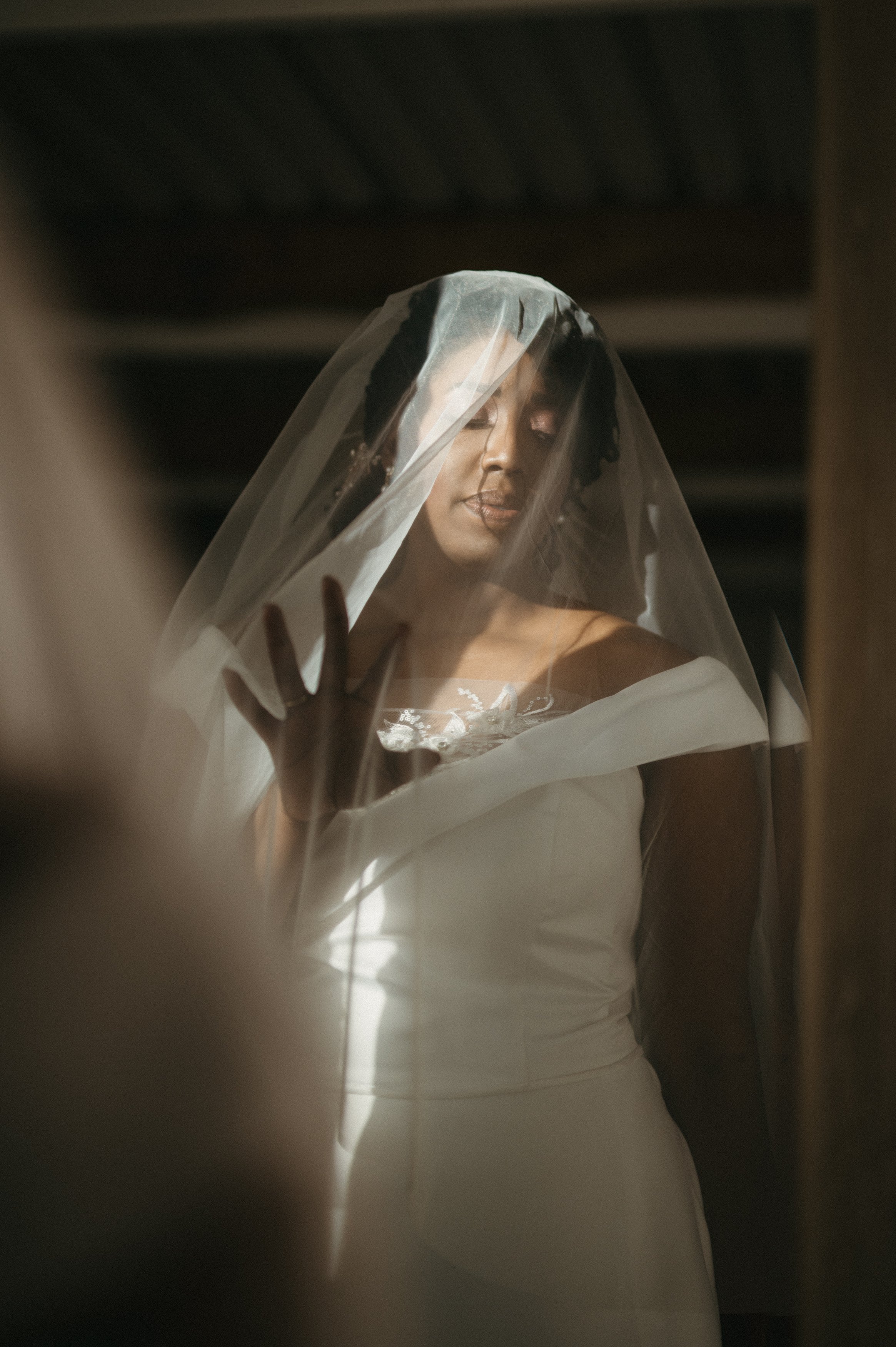 Bride with a veil touching the glass, her eyes closed in a contemplative moment.