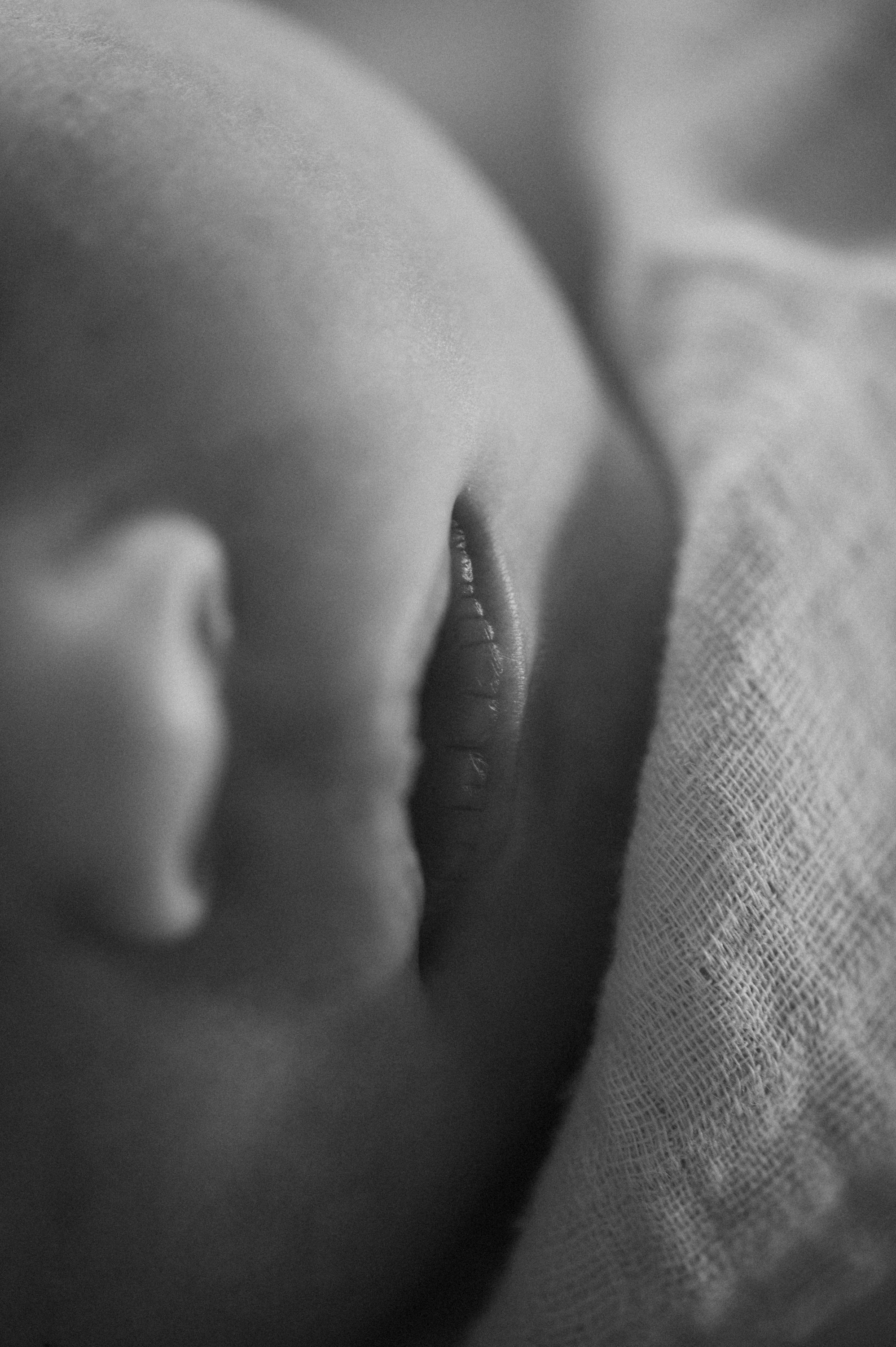Close-up black and white photo of a sleeping baby's face, focusing on lips and nose.