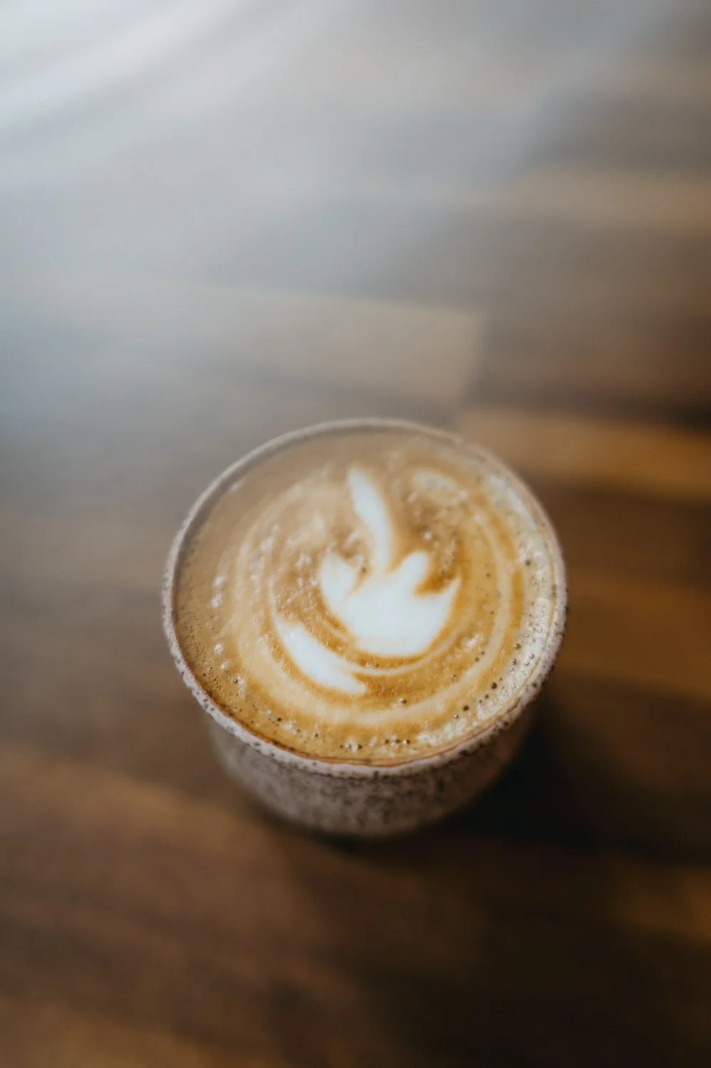 Top view of a coffee drink with latte art on a wooden surface.