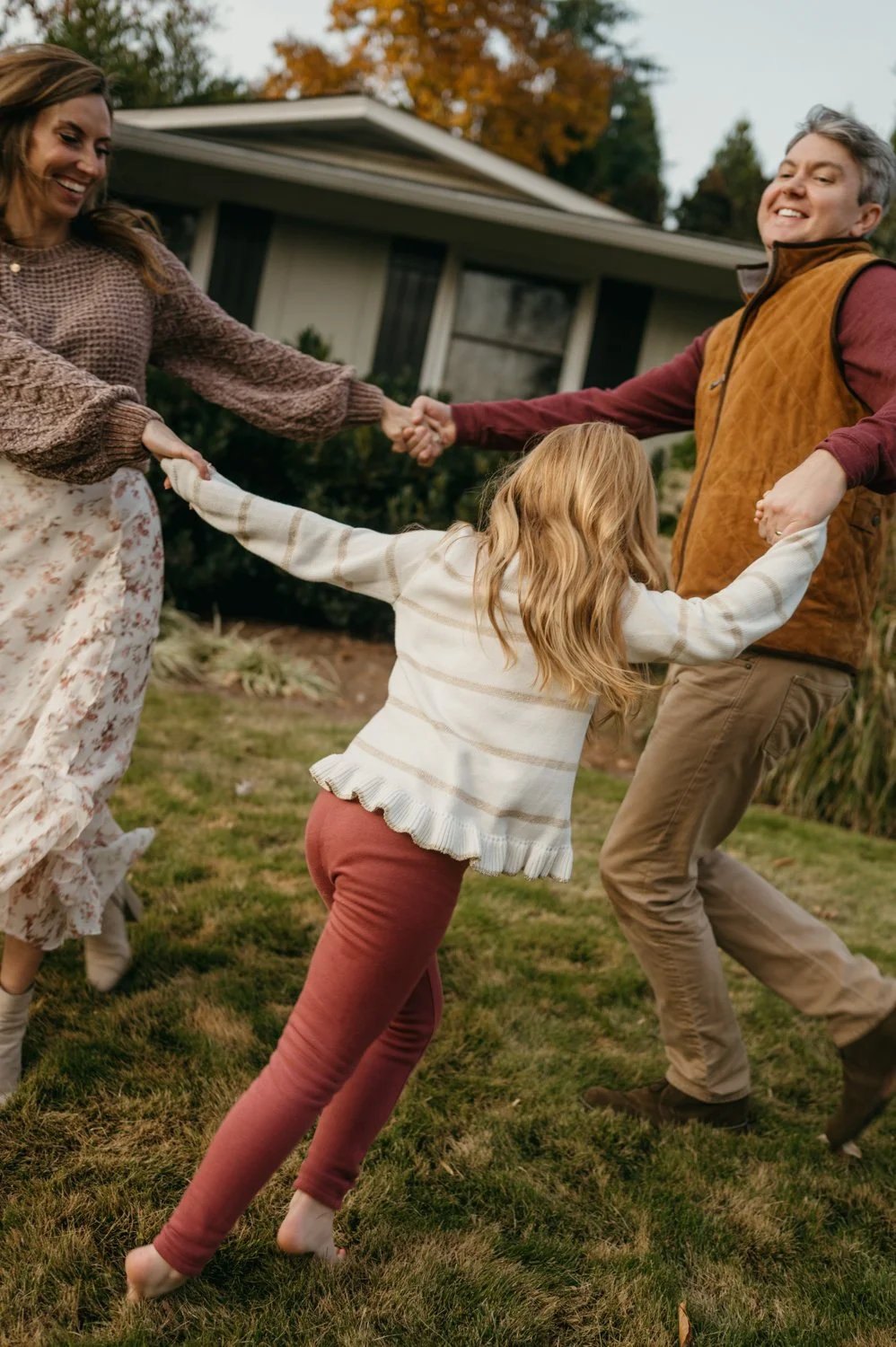 A family playing tug-of-war outdoors on a grassy yard with a house in the background, during fall.