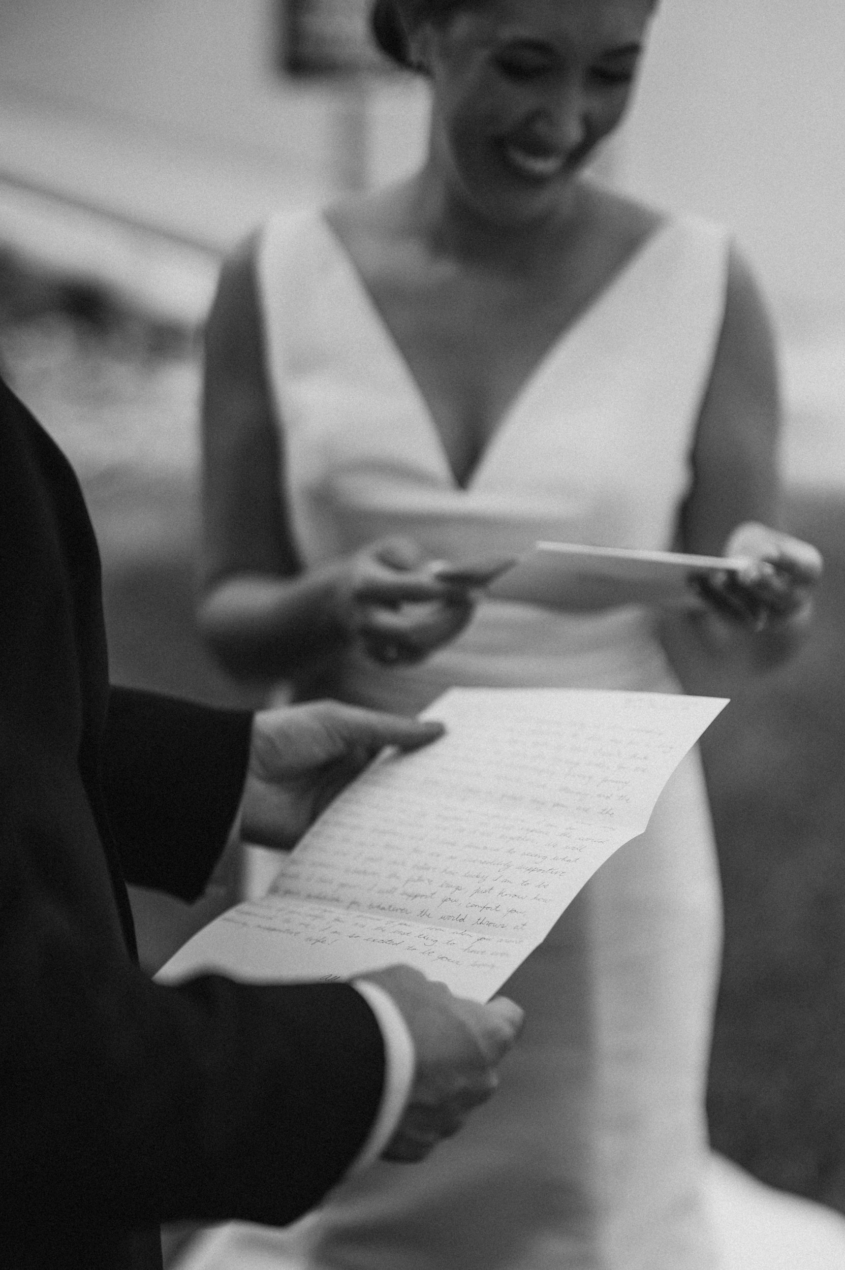 A woman in a white dress smiling and holding a prayer book during a wedding ceremony.