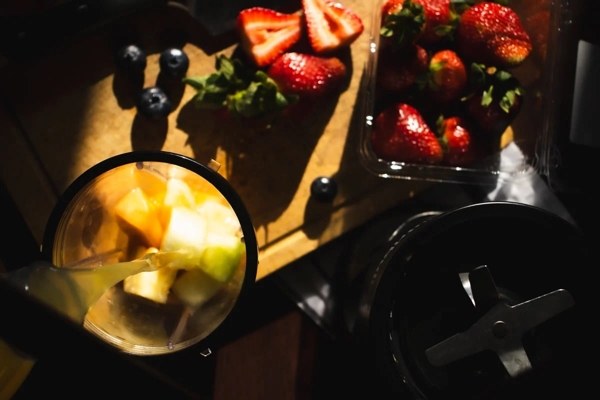 nutri bullet preparation space with strawberries, blueberries, and fruit and juice being poured into the cup