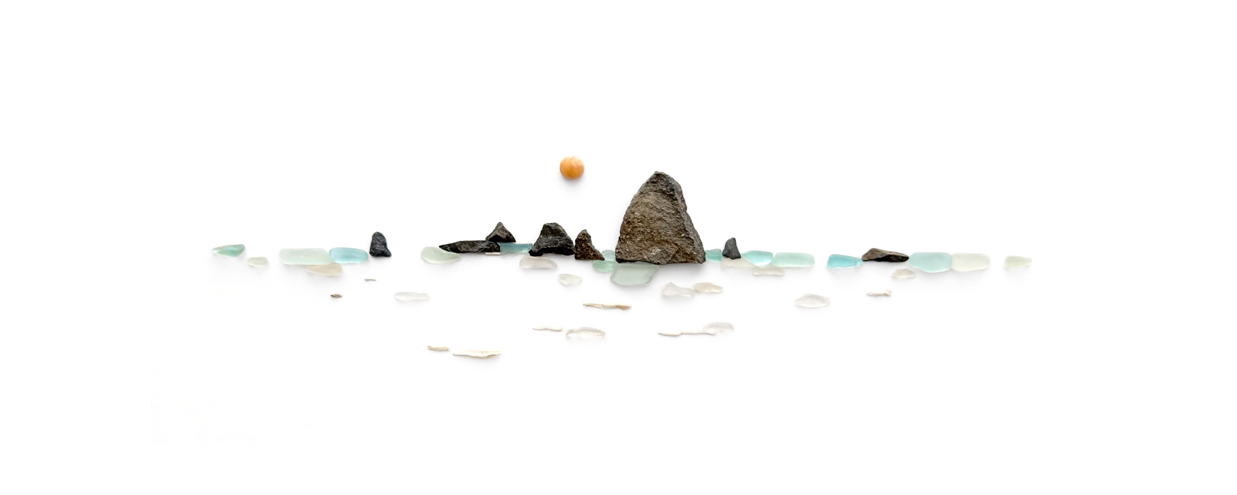 Sea glass ocean landscape with waves, shoreline stones, and rising sun