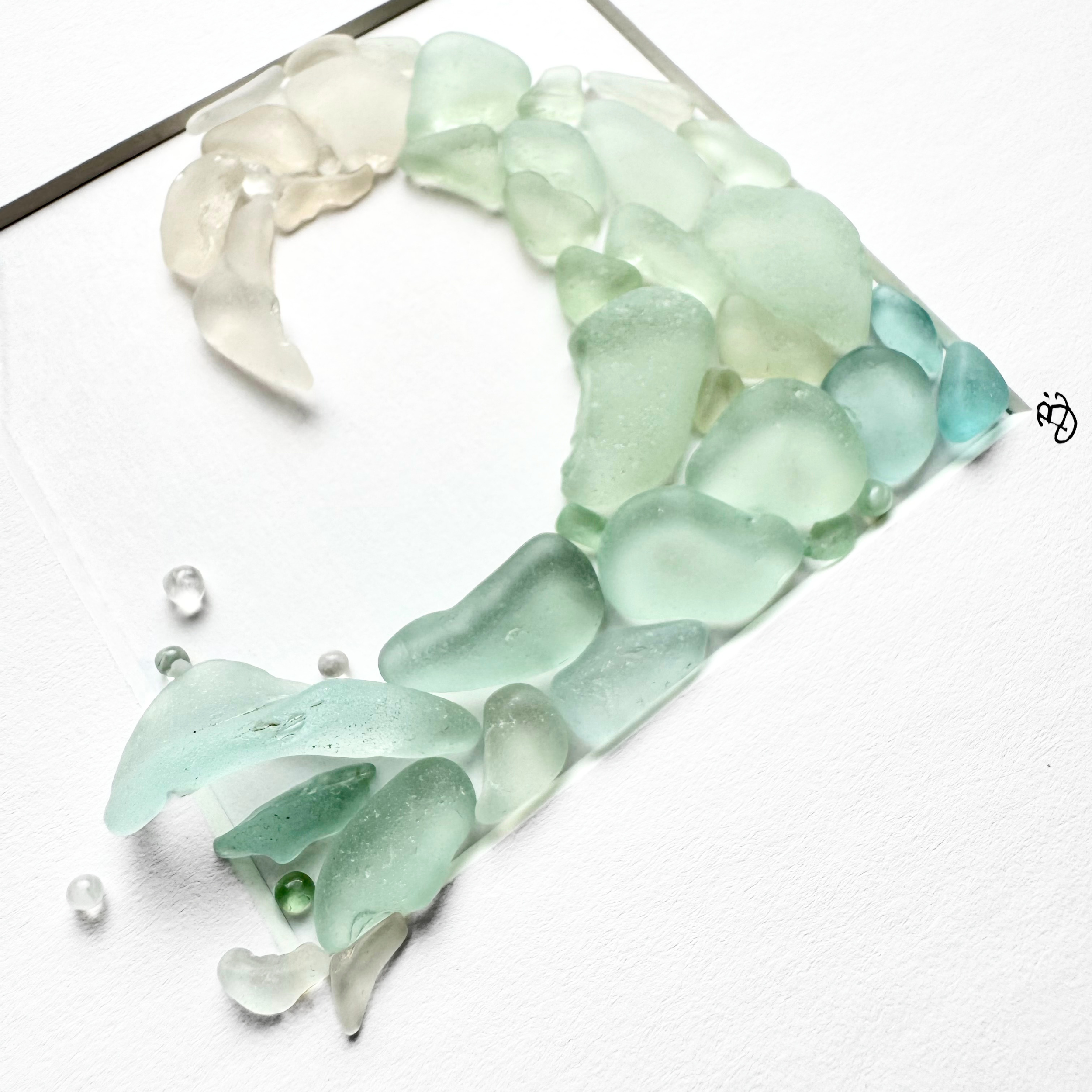 Curling ocean wave created from layers of aqua and white sea glass.